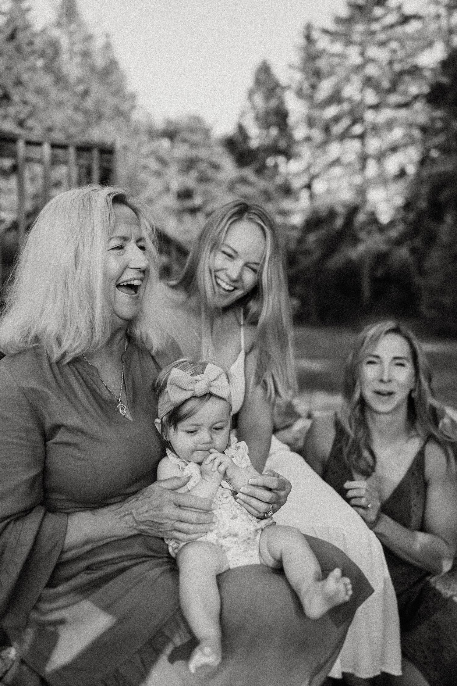 A joyful multi-generational family moment captured in black and white in a garden setting.