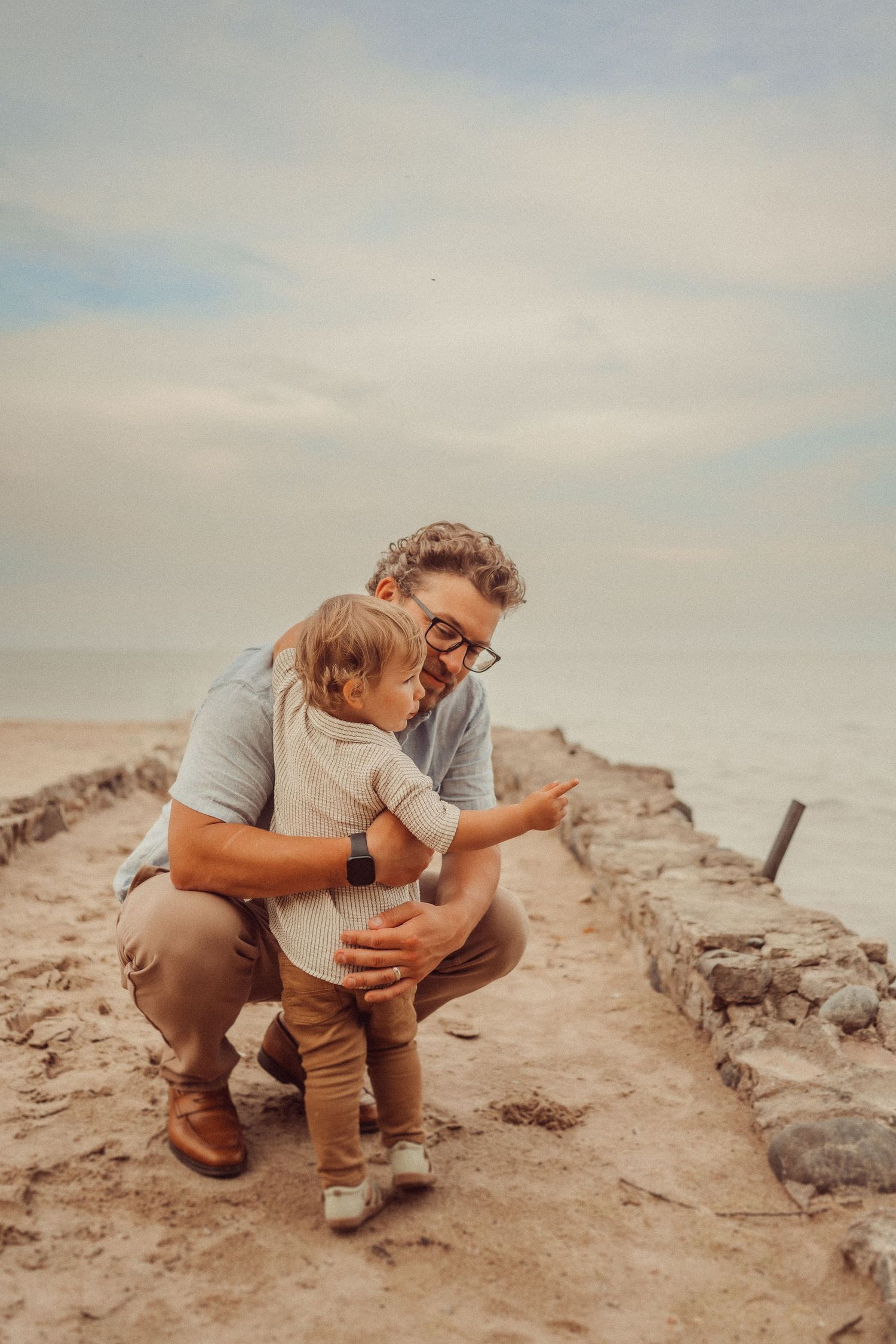 Tender moment shared between parent and child on rocky coastal path at sunset.