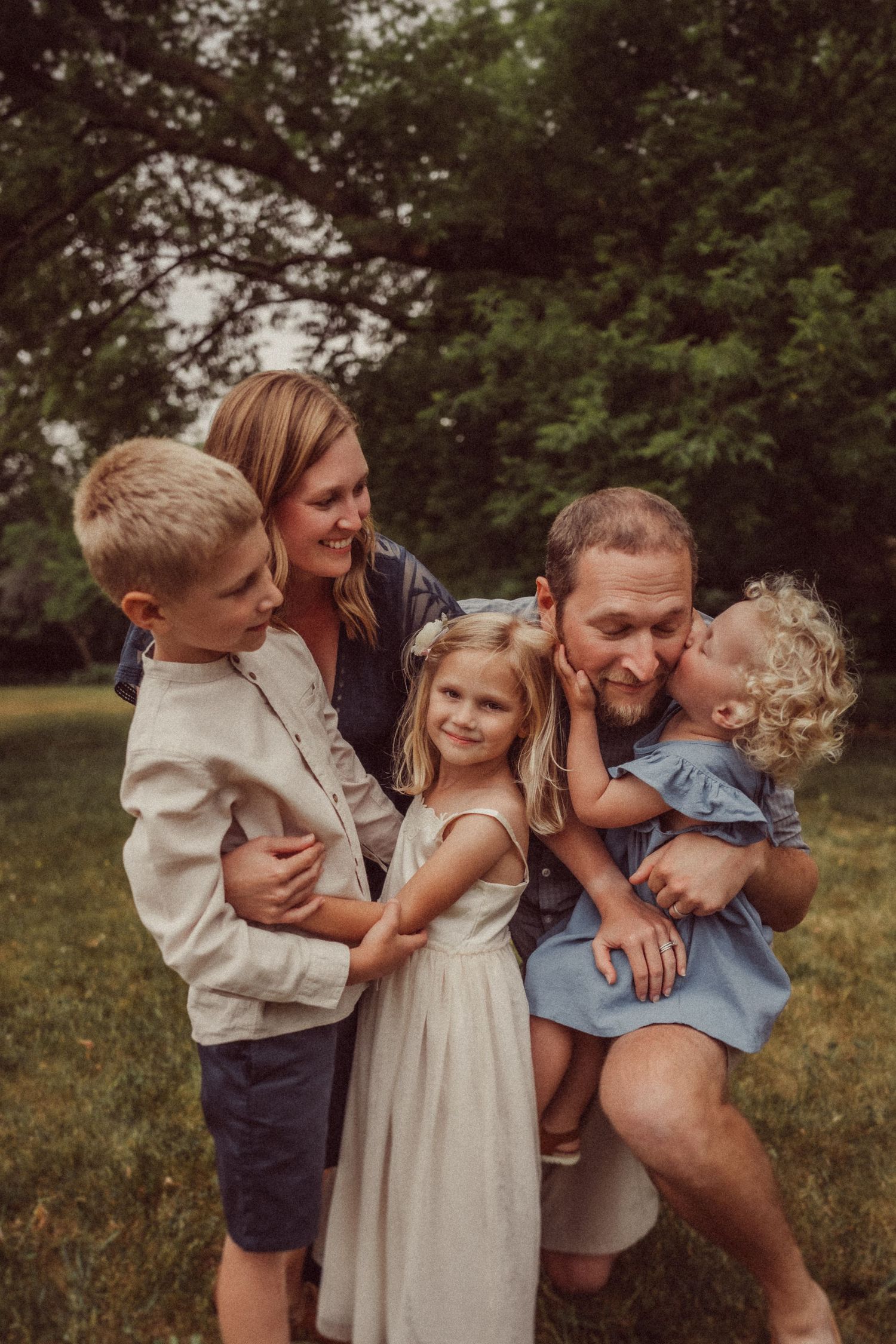 Close family portrait showing tender moments in an outdoor setting.
