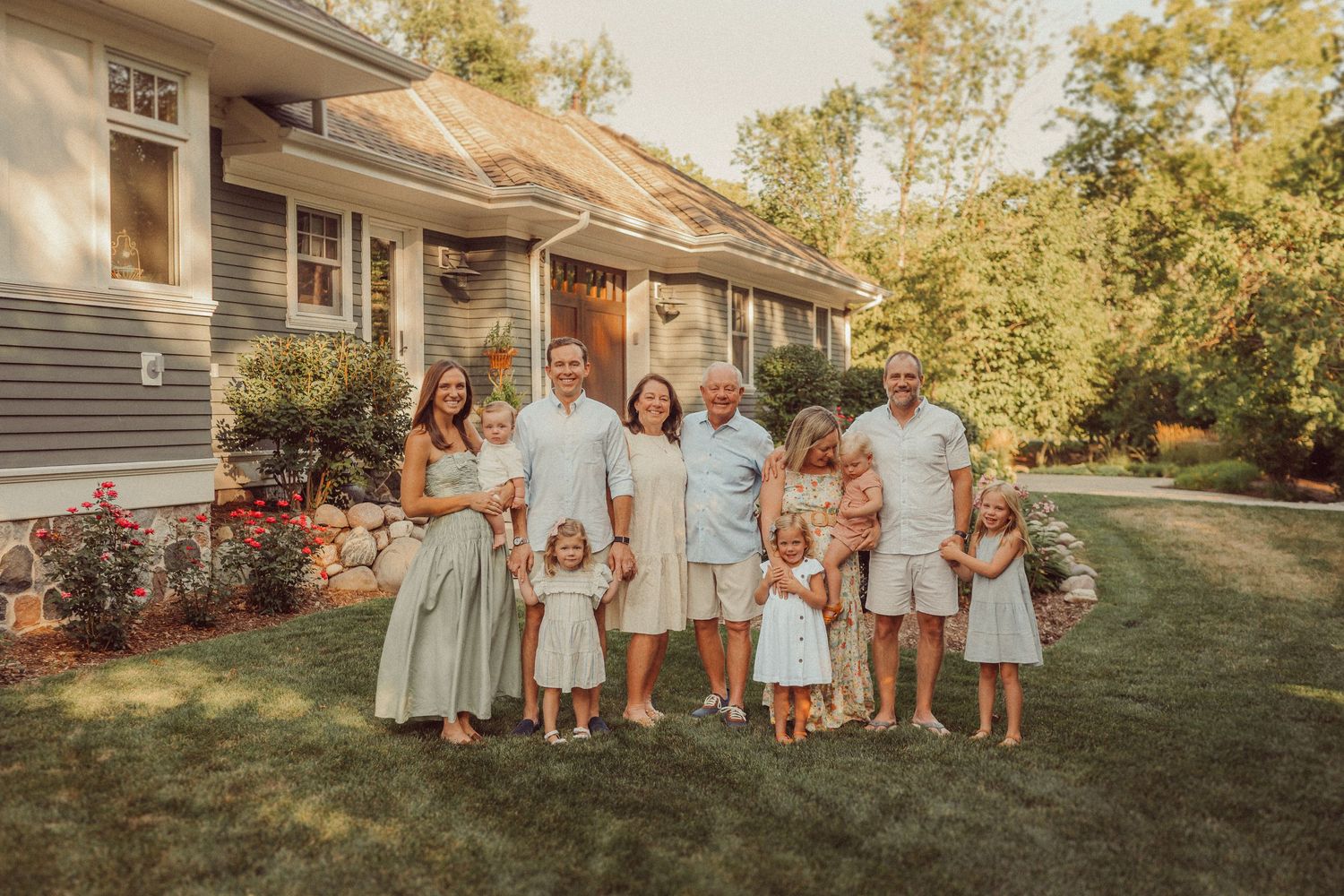 Group portrait of people wearing coordinated outfits standing in front of a house.