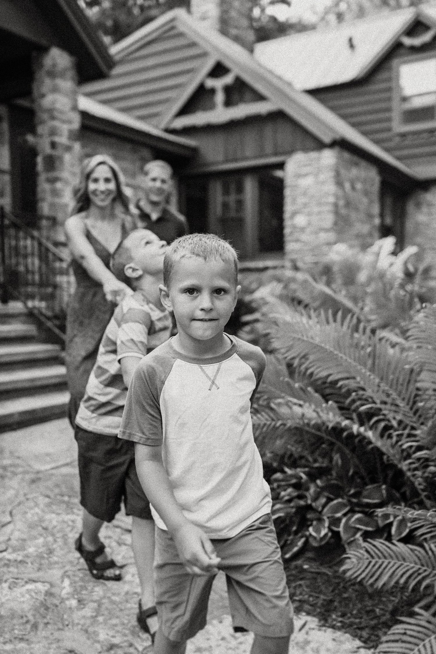 Black and white candid shot of family members outside stone cottage entrance.
