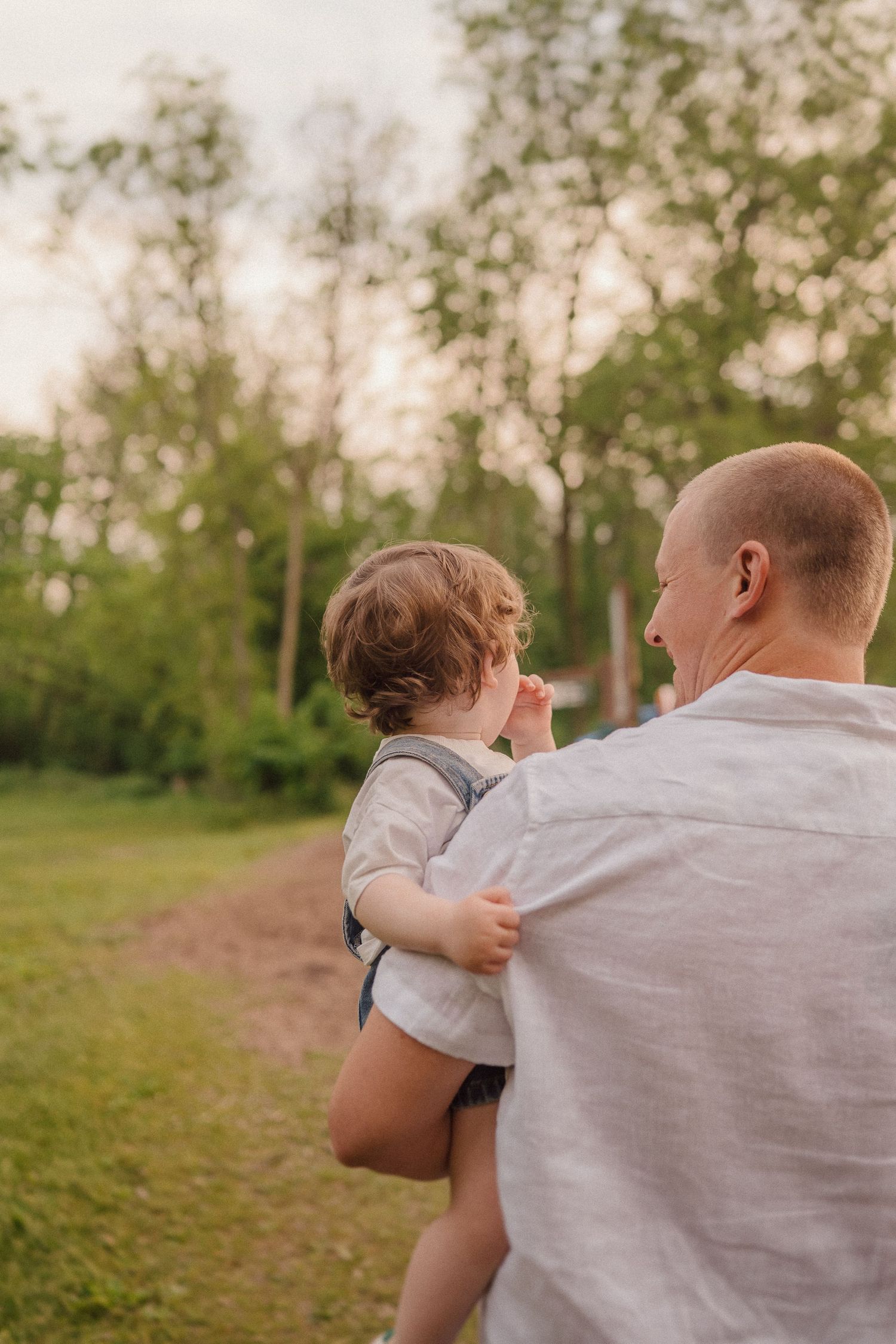 Parent and child share tender moments together in a green summer field at golden hour.