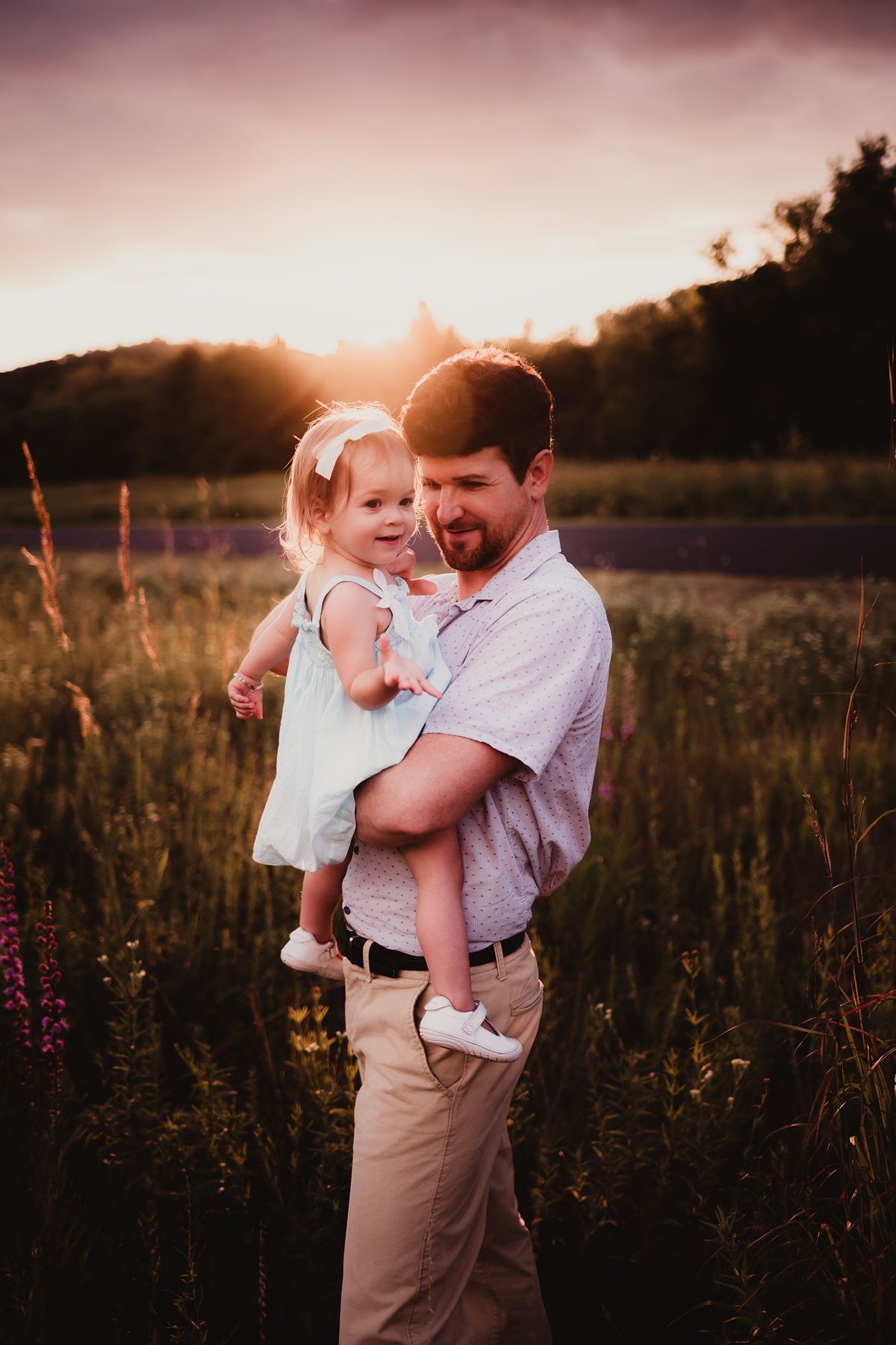 Sweet embrace captured in warm sunset light among purple wildflowers.