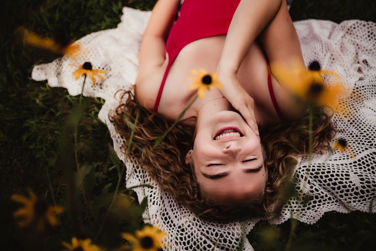 Artistic overhead portrait on lace blanket surrounded by yellow wildflowers in golden light.