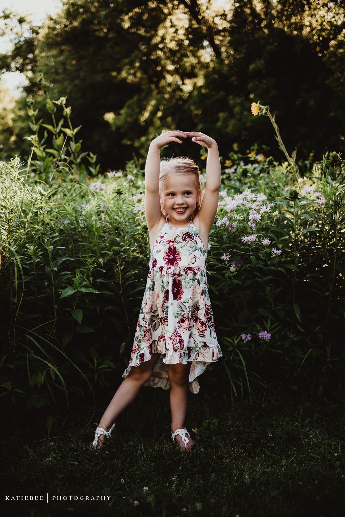 Candid portrait of someone in a floral dress dancing joyfully in a garden setting.