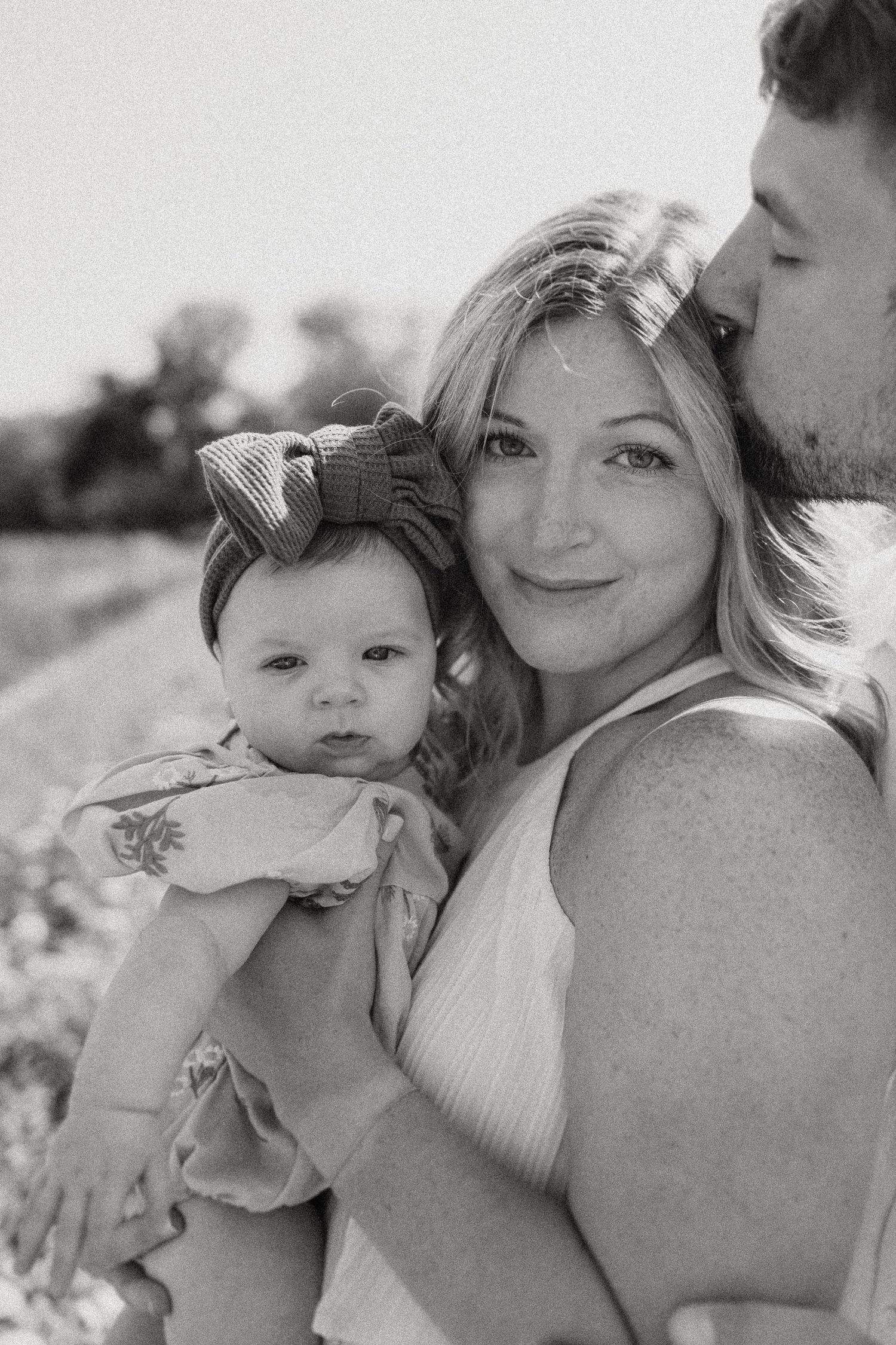 A tender family moment captured in black and white photography outdoors.