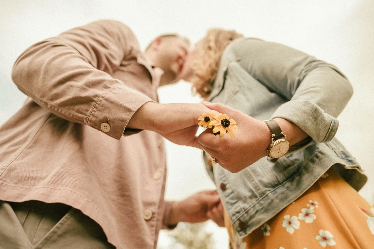 Couple sharing a playful moment with flowers in casual outdoor setting.