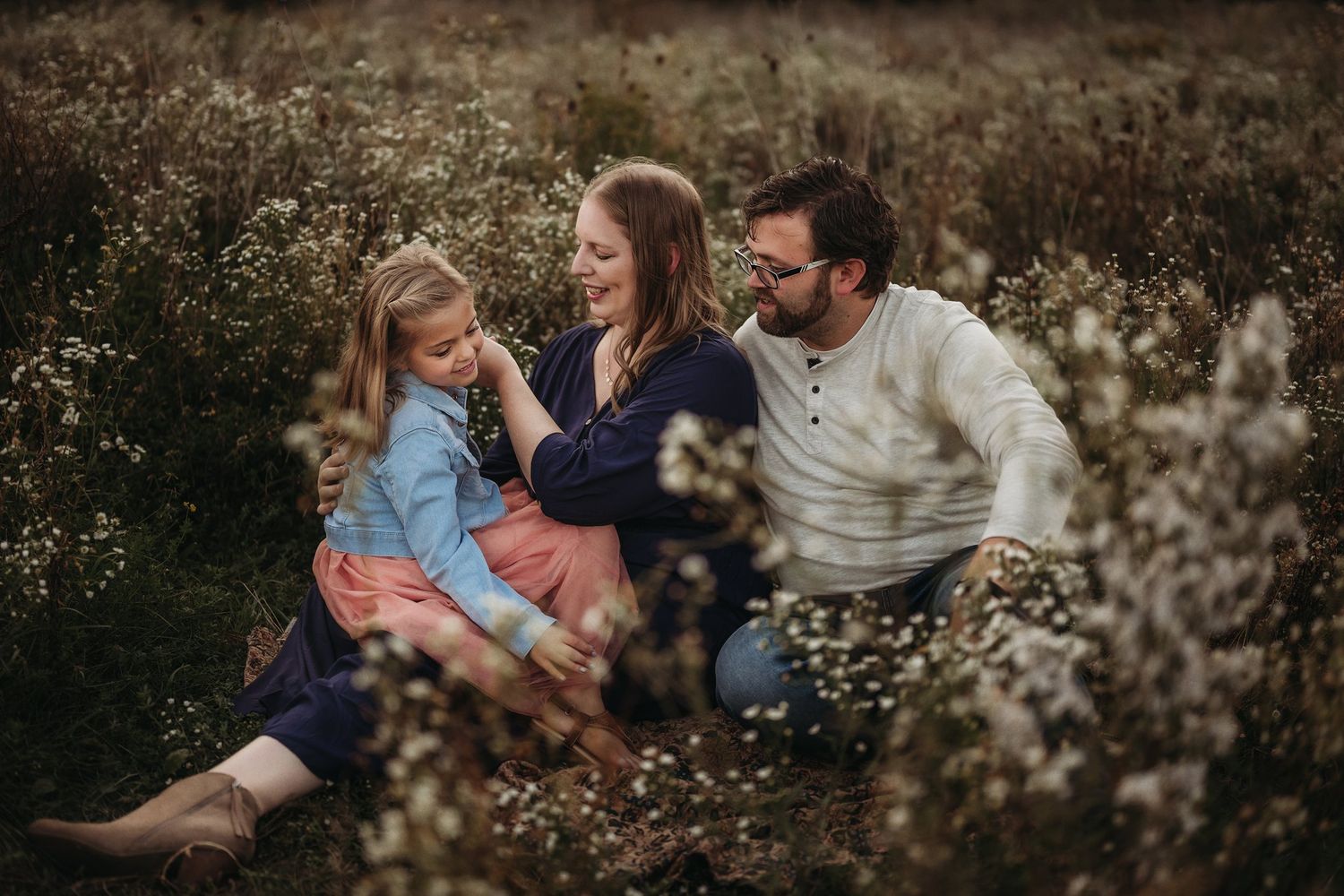 Joyful family moment captured among blooming wildflowers during golden hour.
