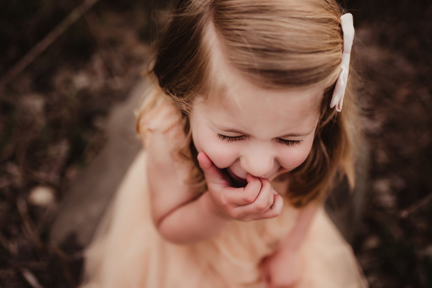 A candid moment captures pure laughter in a peach-colored dress.