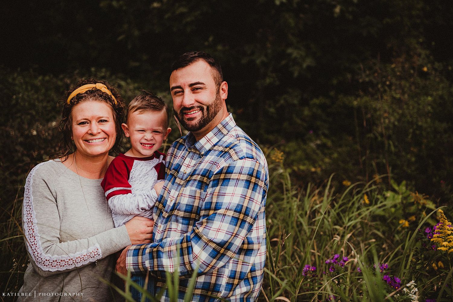 Family portrait outdoors with wildflowers in background.