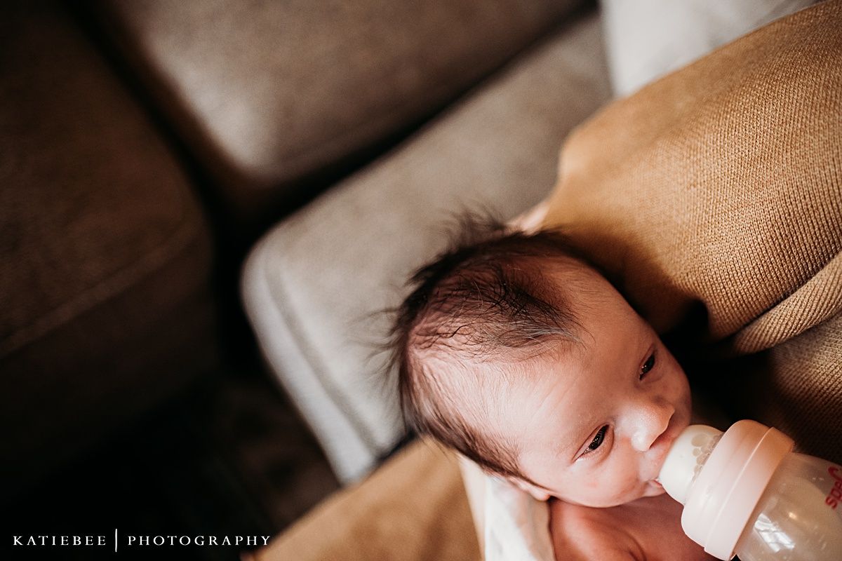 Sleeping newborn baby against beige blanket in soft light.