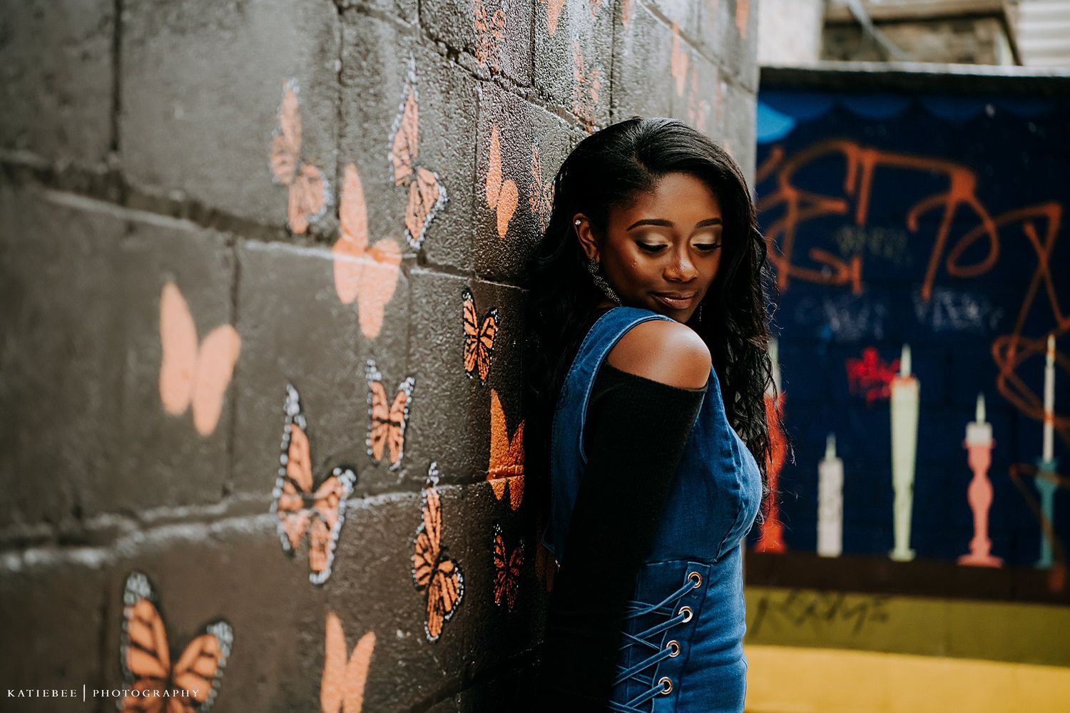 Artistic portrait against a wall decorated with orange butterfly murals.