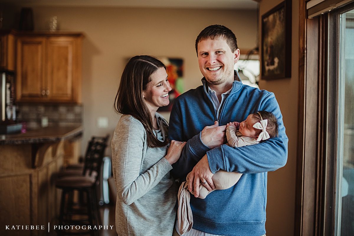 Casual family portrait in kitchen with natural window light during lifestyle photo session.
