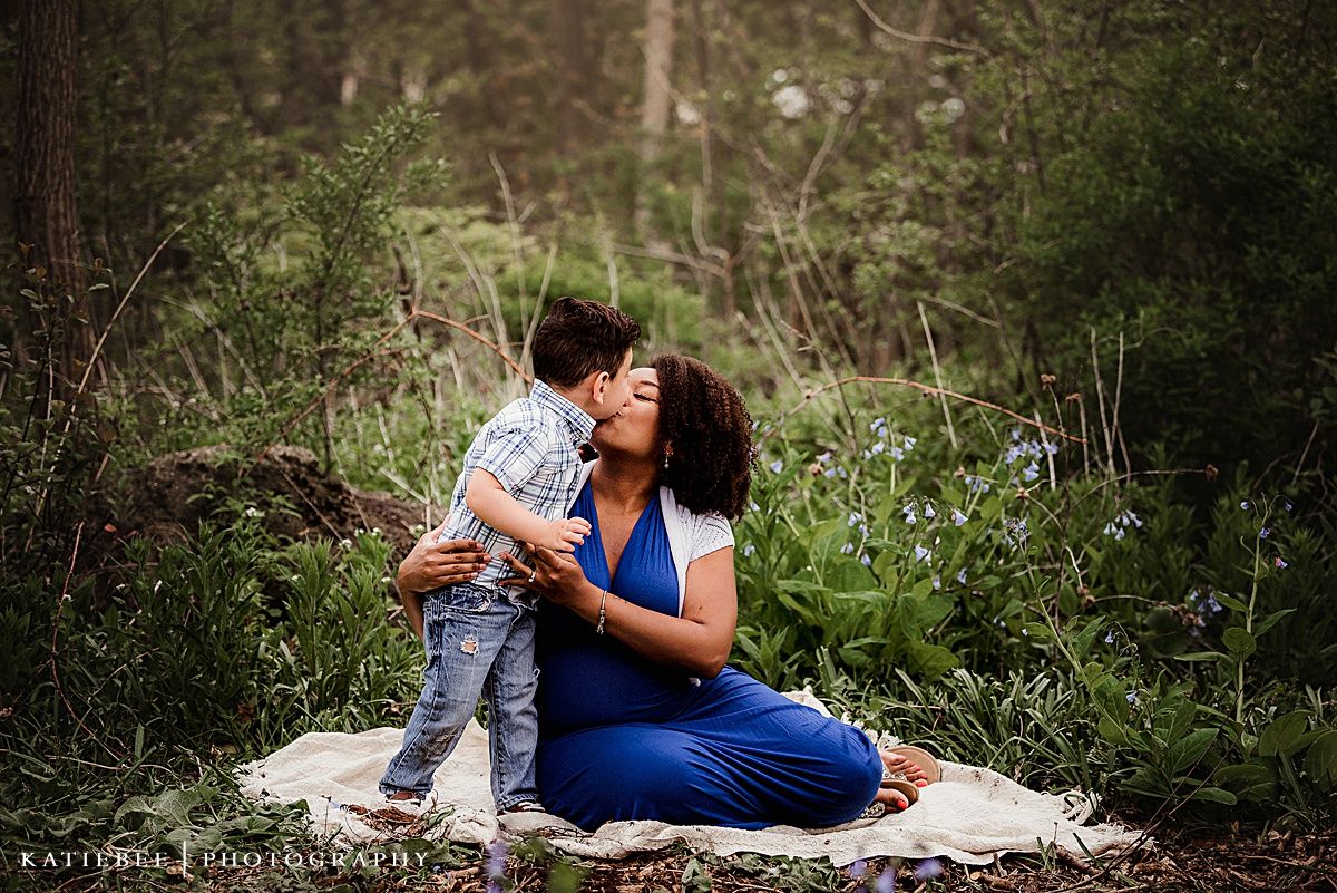 Sweet moment captured between mother and child embracing on a blanket in a natural outdoor setting.