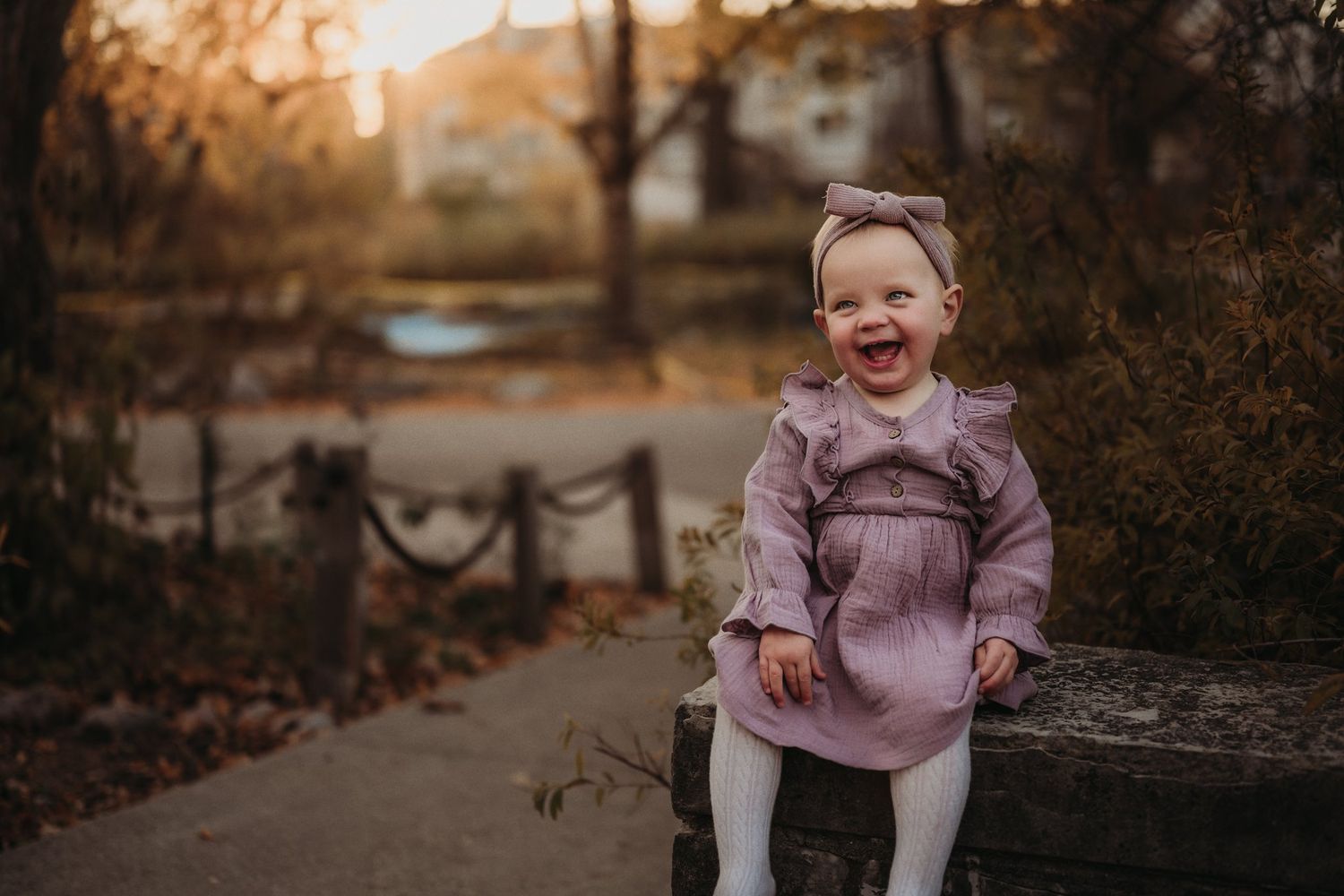 Joyful expression while sitting on wooden fence in autumn setting.