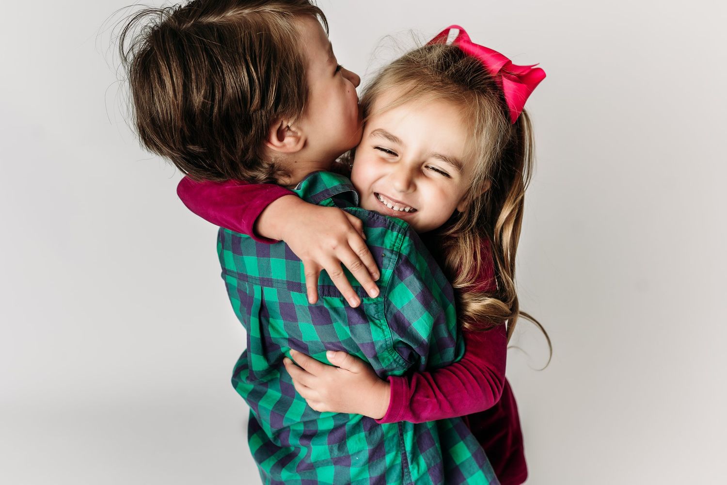 Sweet moment captured as two children share an affectionate hug against white background.