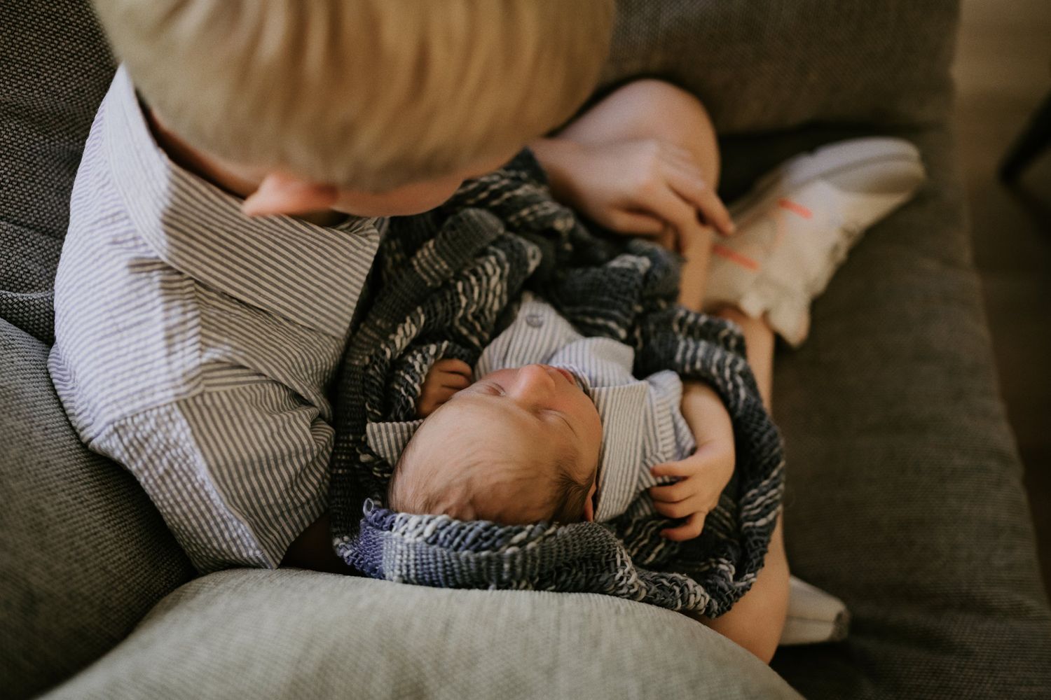 A small child and baby interact playfully while resting on a comfortable sofa.