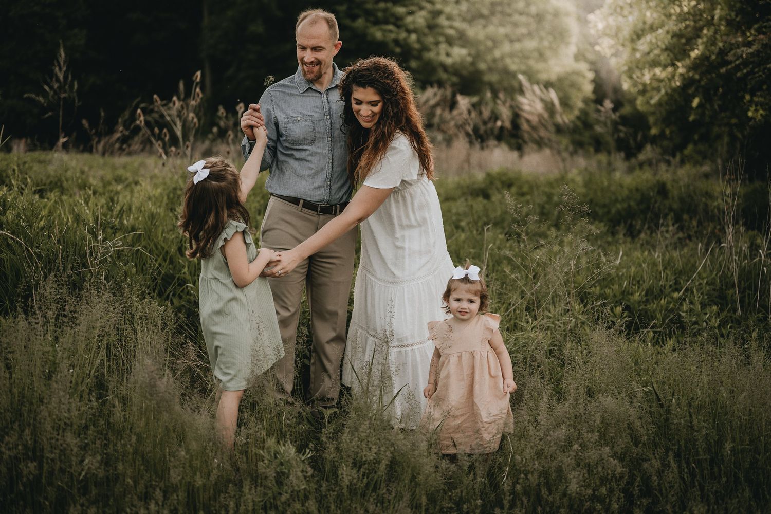 Golden hour family photoshoot in a wild grass field showing loving interactions and natural moments.