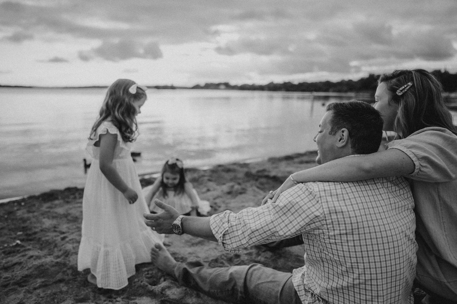 A casual family gathering on the beach with dramatic cloudy skies in the background.