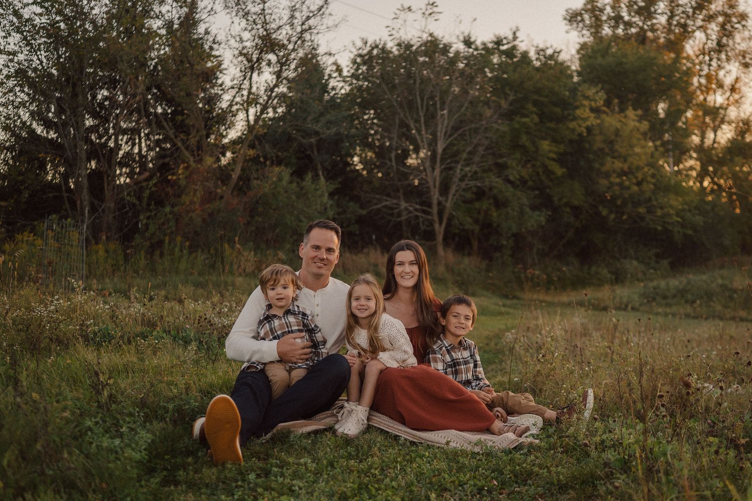 A family portrait session in a golden meadow with natural autumn lighting.