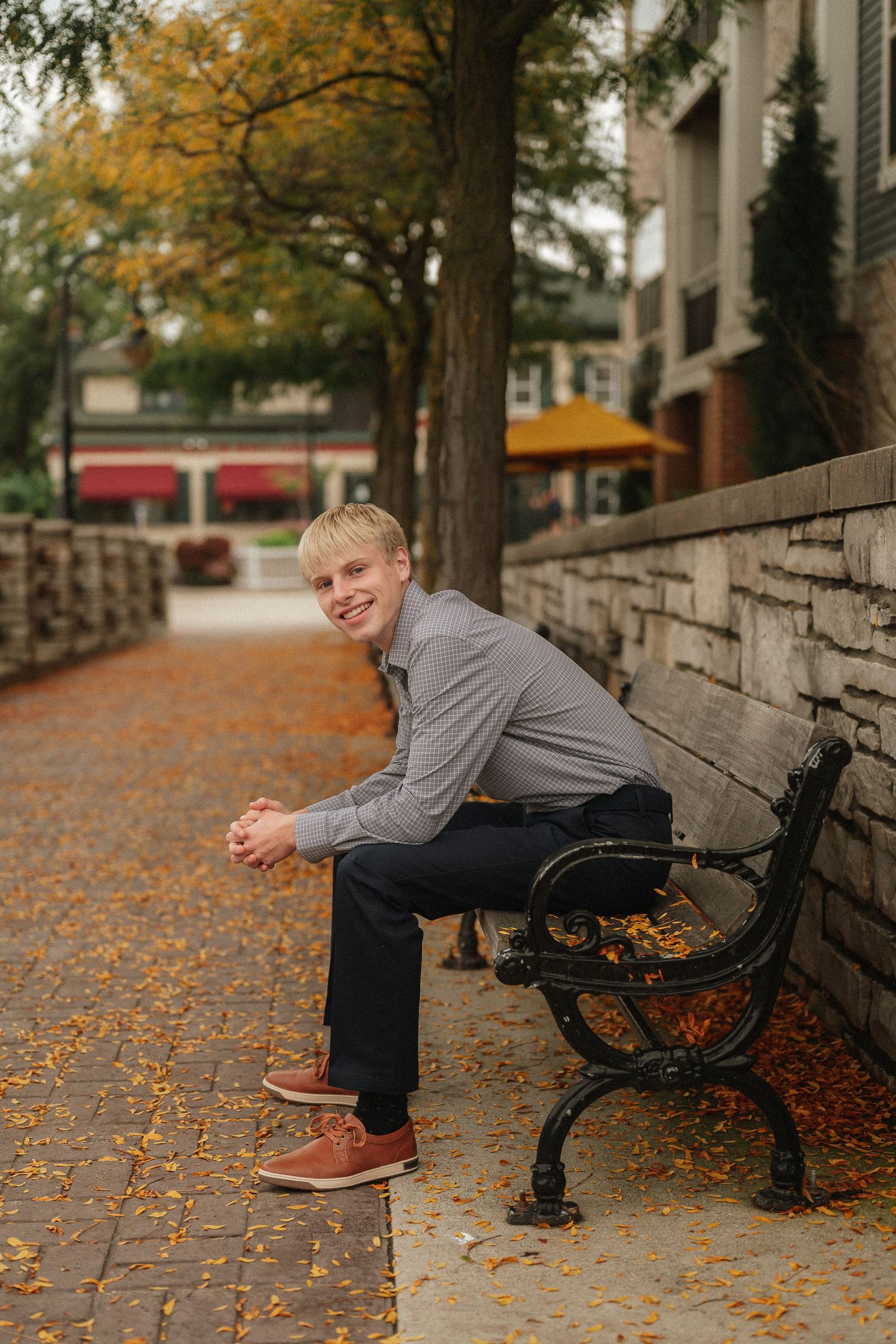 Autumn scene on a park bench surrounded by fallen leaves and stone architecture.