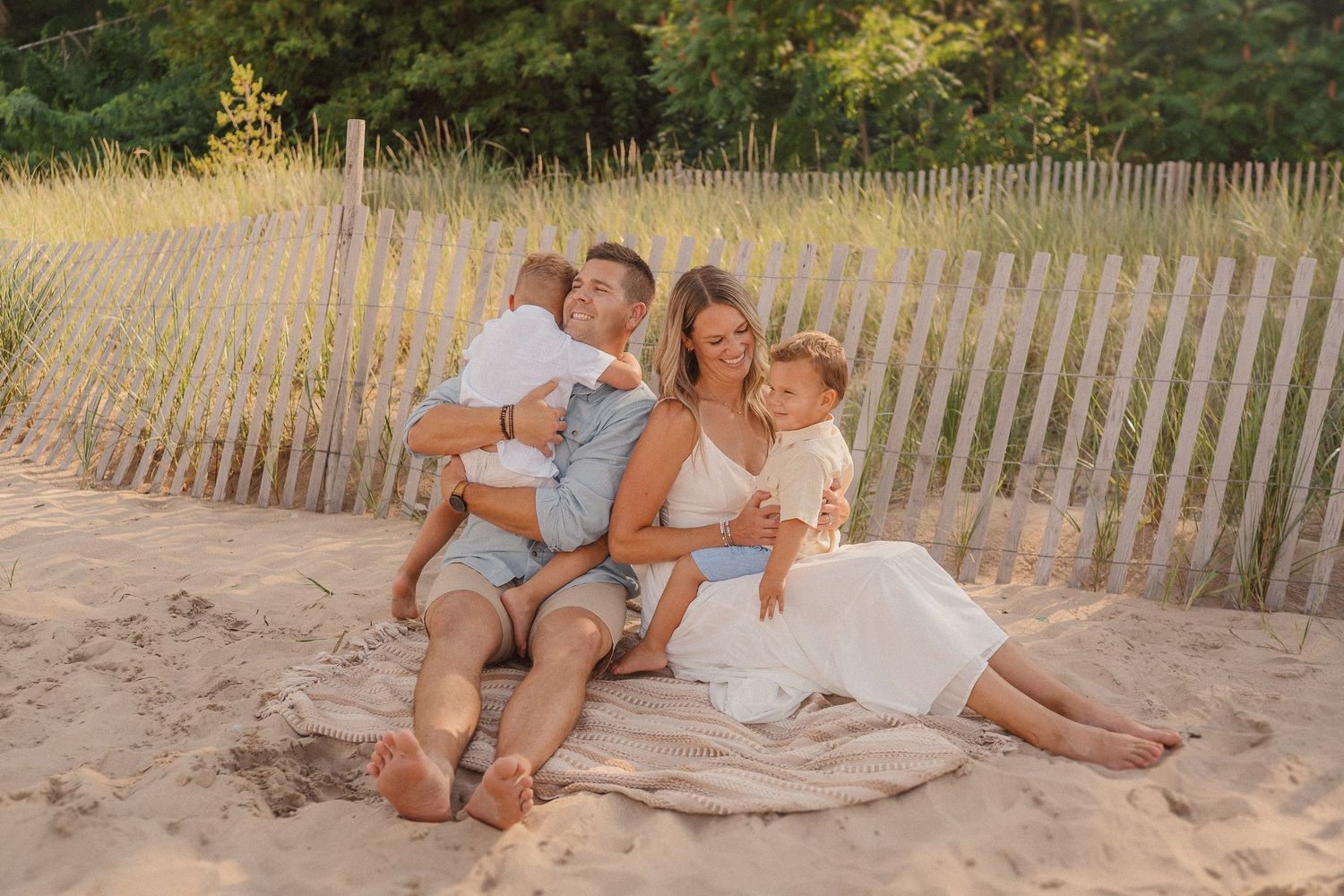 Natural beach portraits captured along sand dunes with wooden fence in late afternoon light.