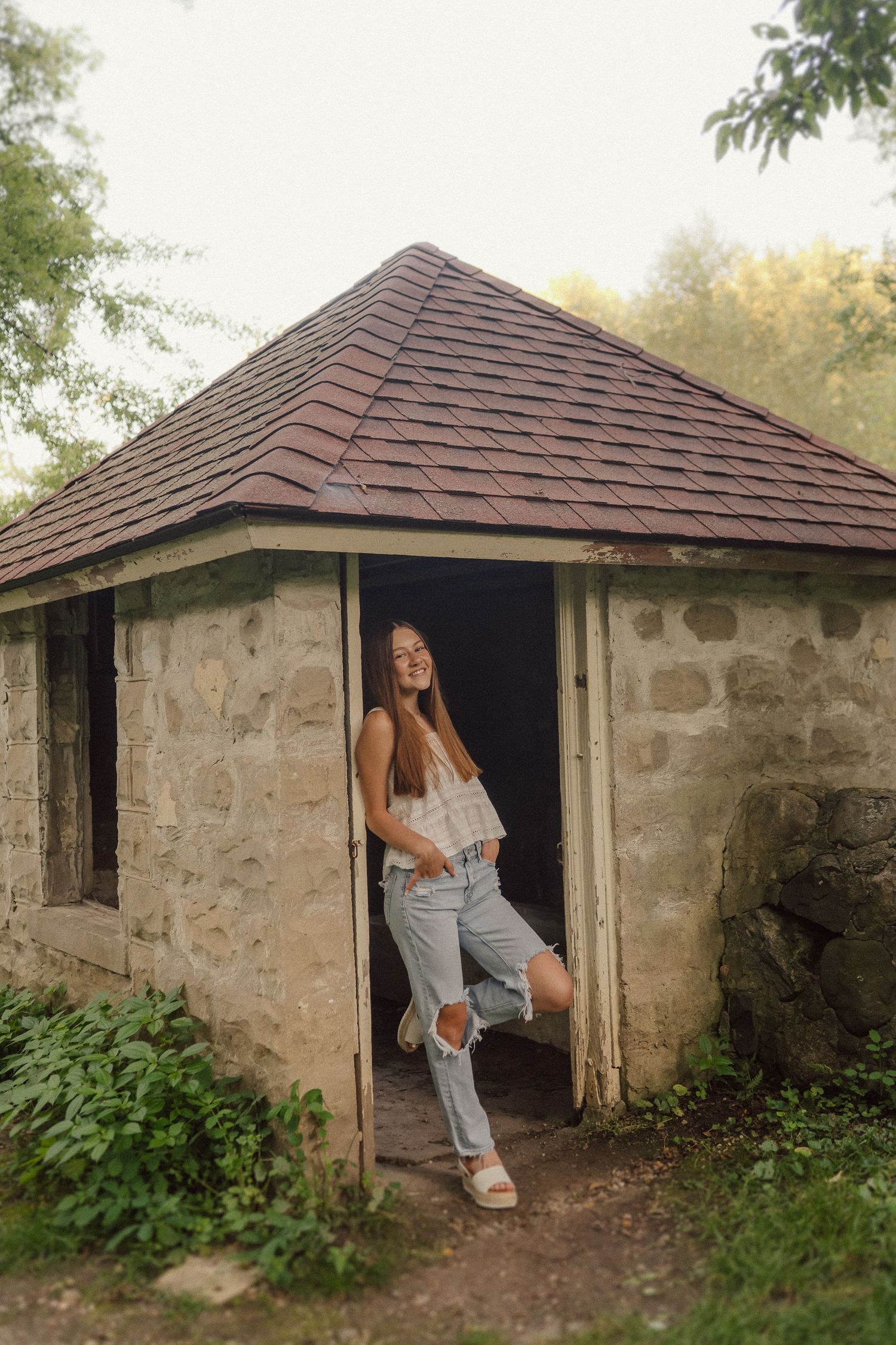 Rustic stone cottage with brown roof surrounded by greenery captured in a series of moody exterior shots.