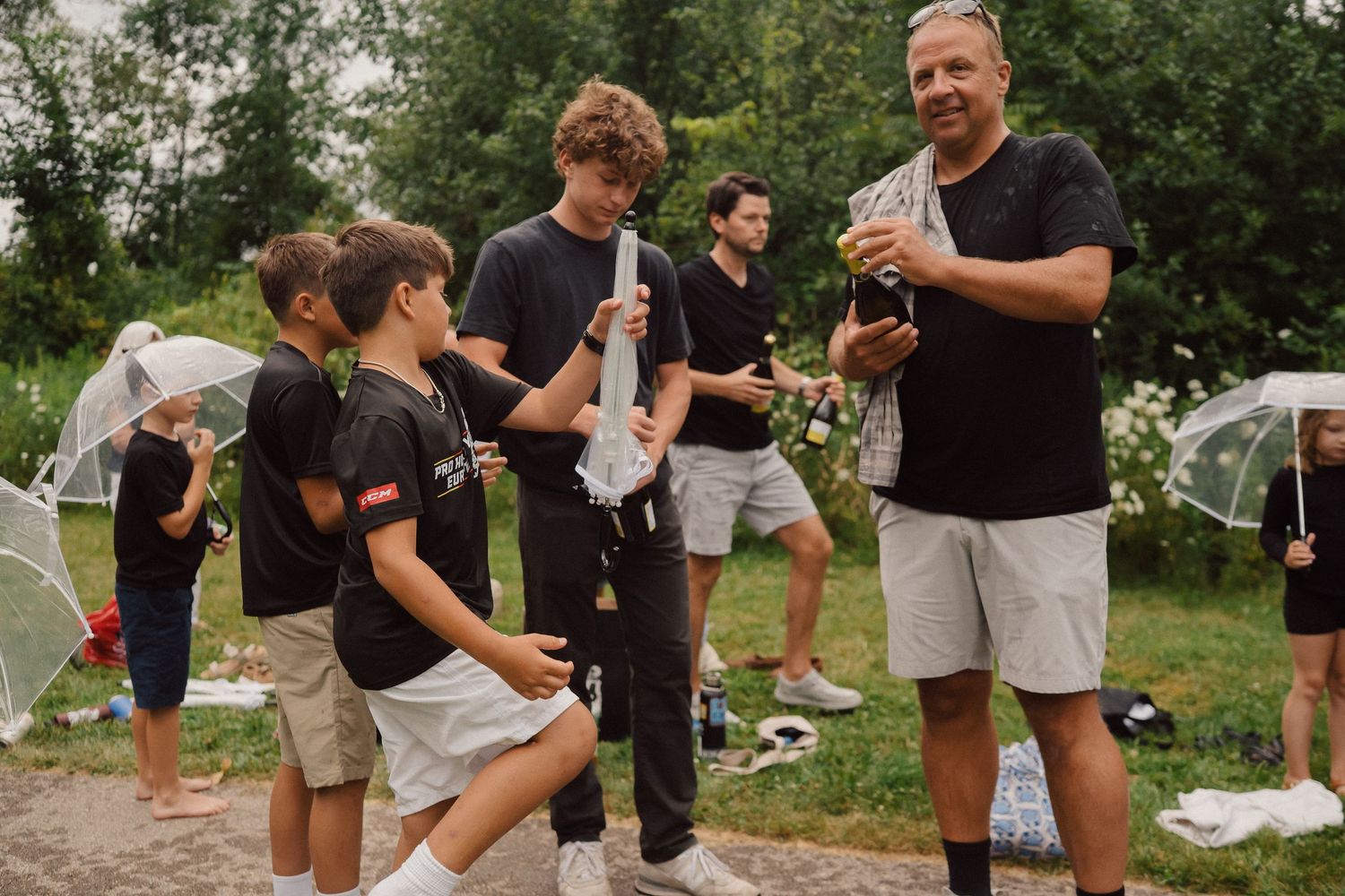 Group of people in black shirts and khaki shorts playing outdoor party games.