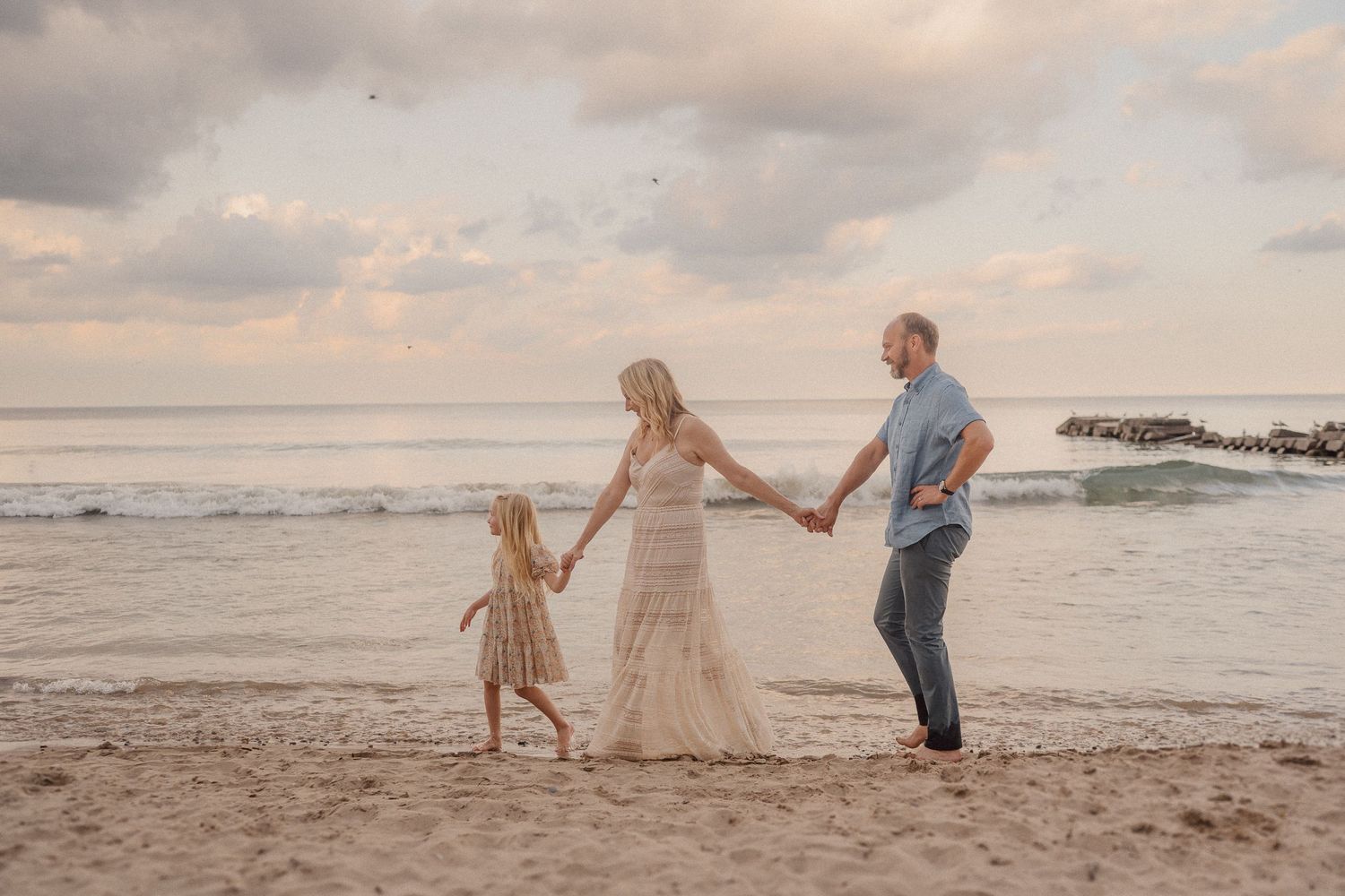 Five connected photos show a couple walking and dancing together on a sunset beach with flowing dresses and ocean views.