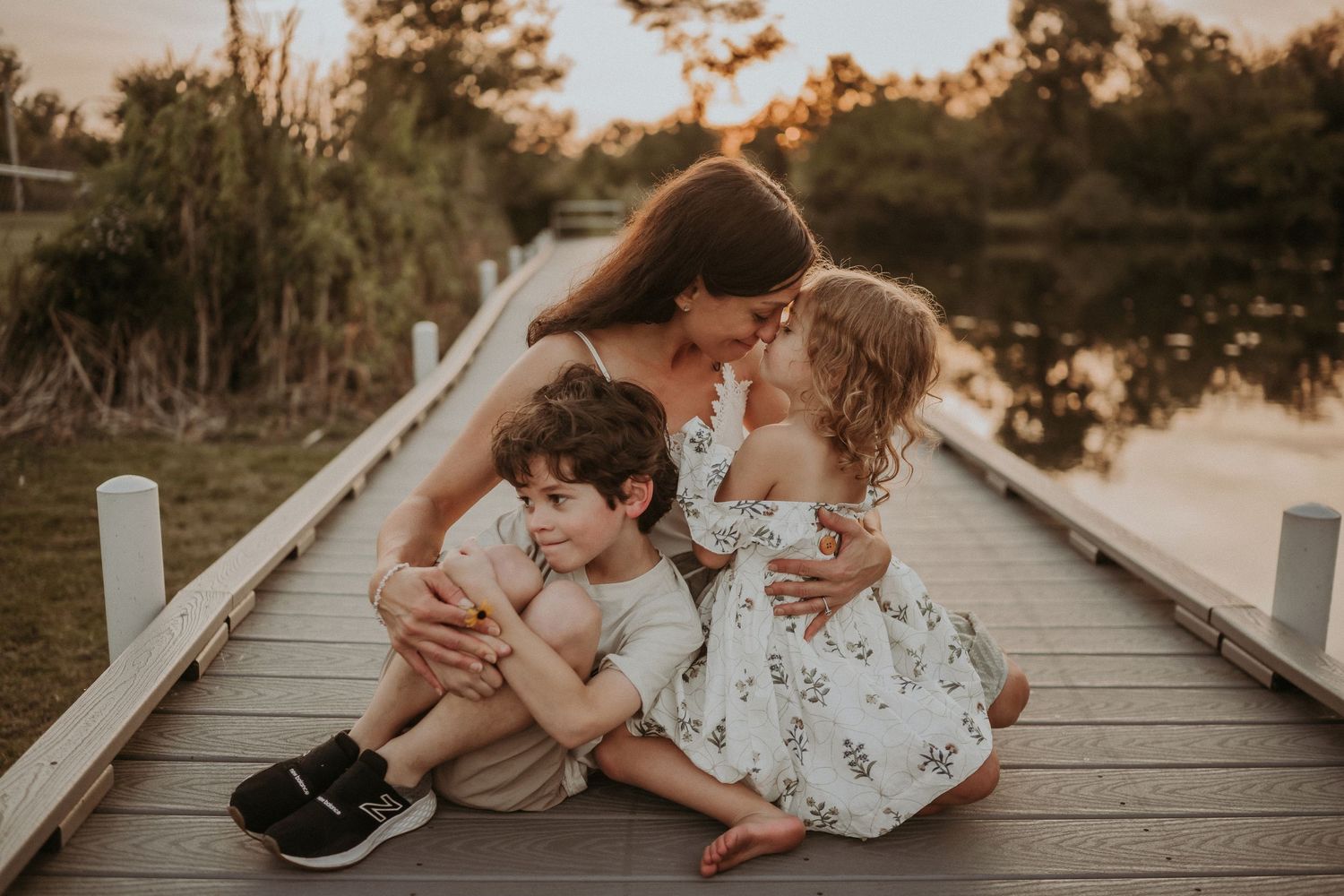 A tender family moment shared on a wooden dock during golden hour.