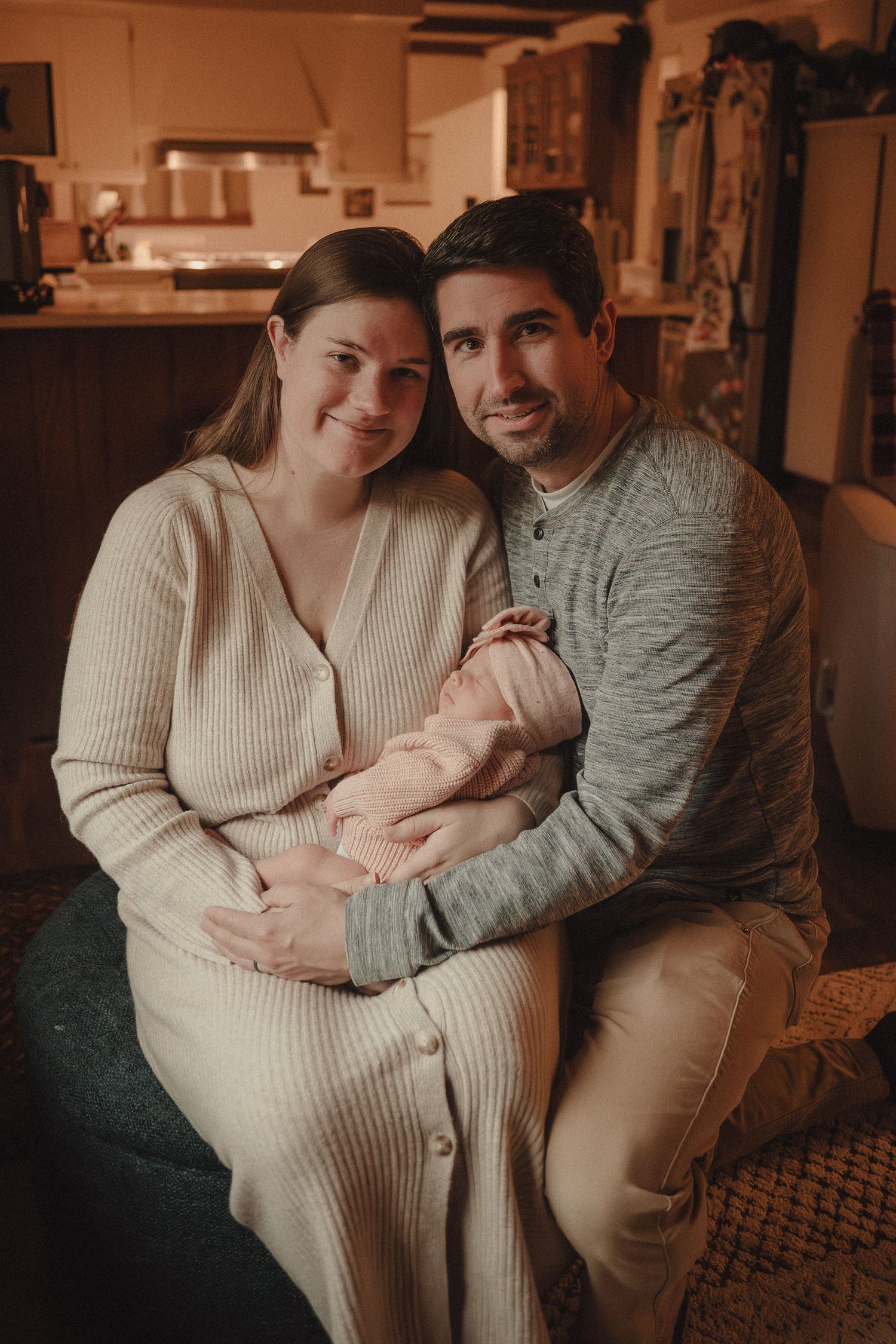 A warm indoor family portrait showing tender moments with a newborn in a cozy living room setting.