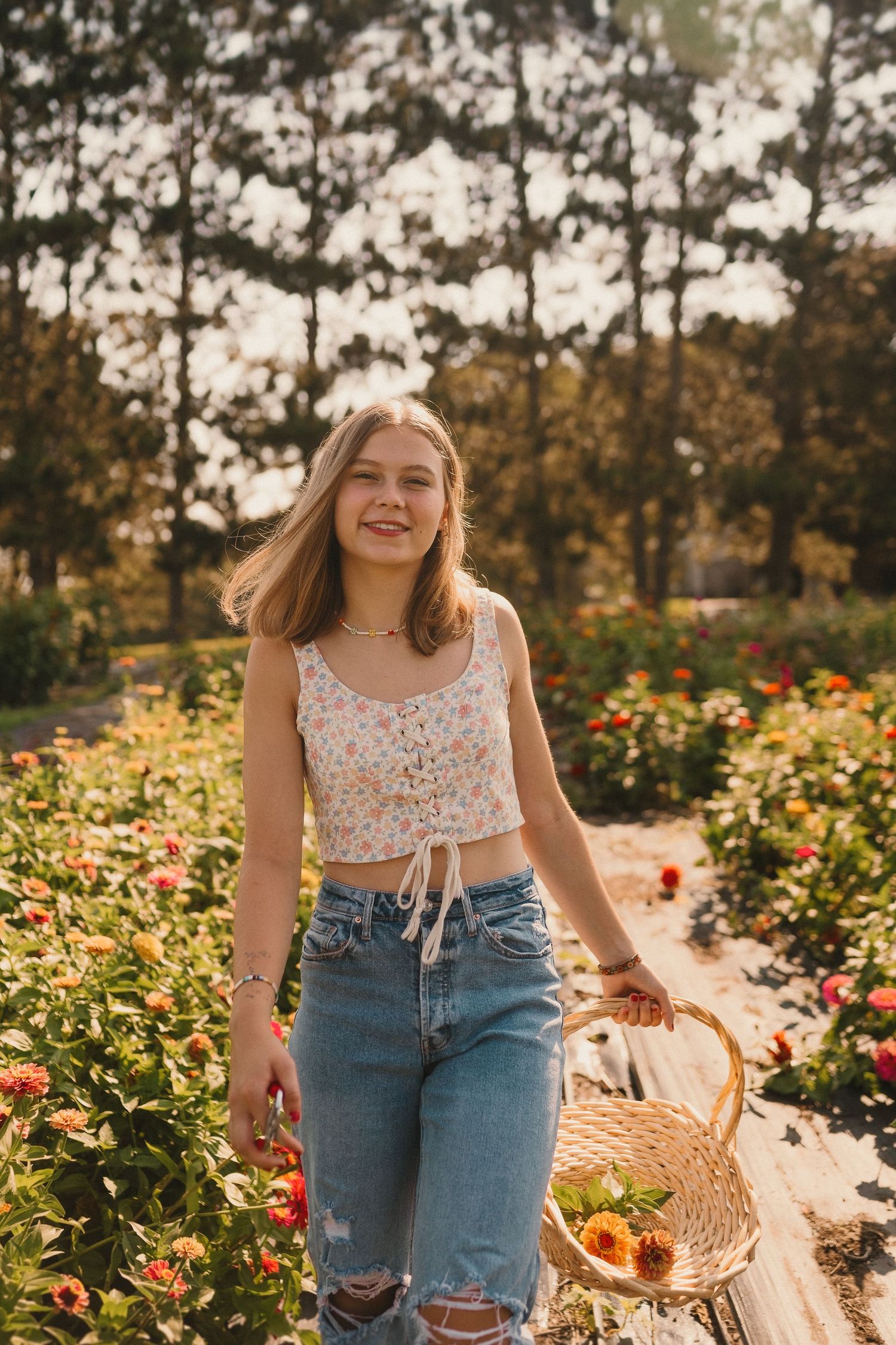 A floral garden scene in warm sunlight with distressed denim and a wicker basket among blooming flowers.
