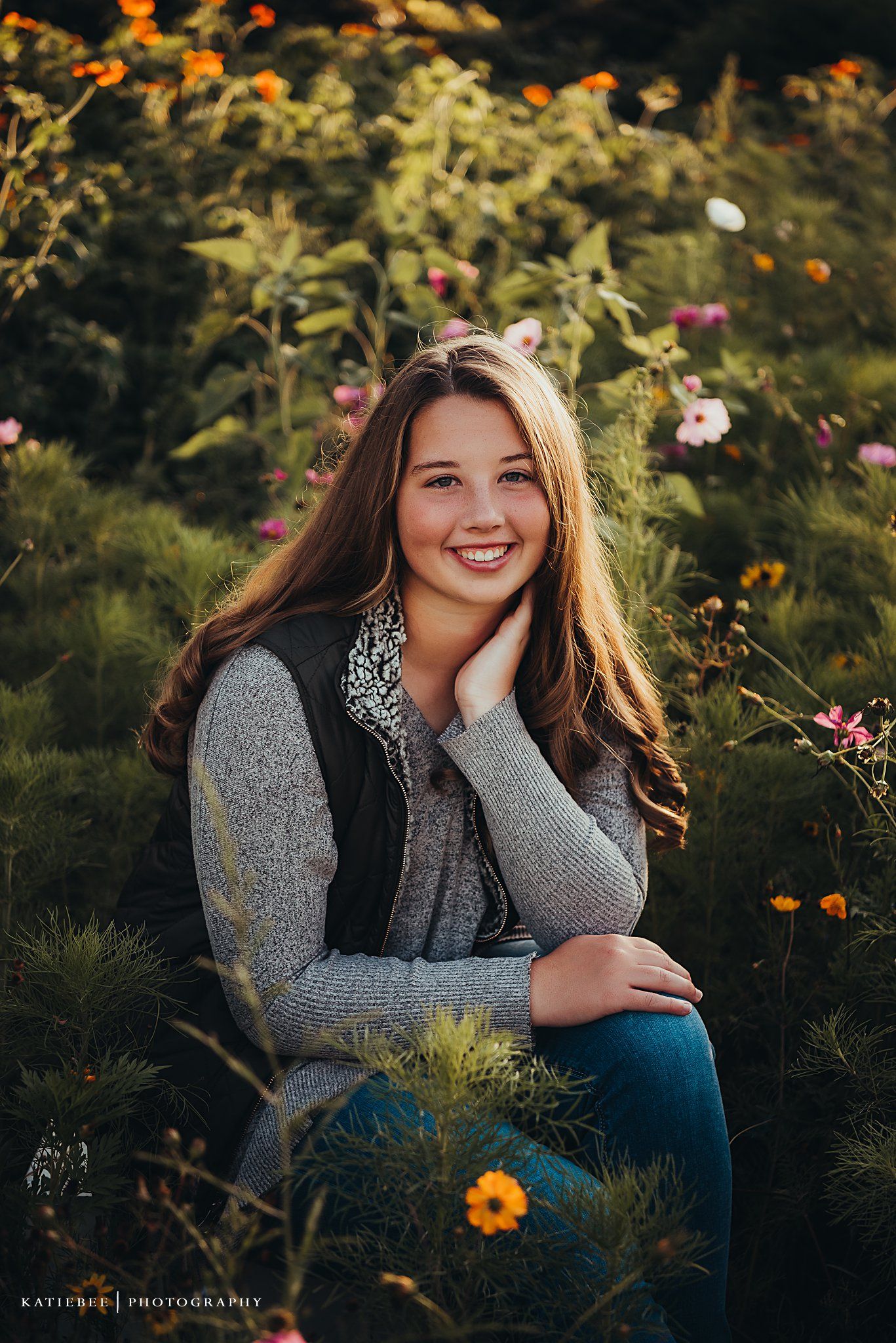 Natural light portrait amidst colorful wildflowers featuring a grey sweater and vest.
