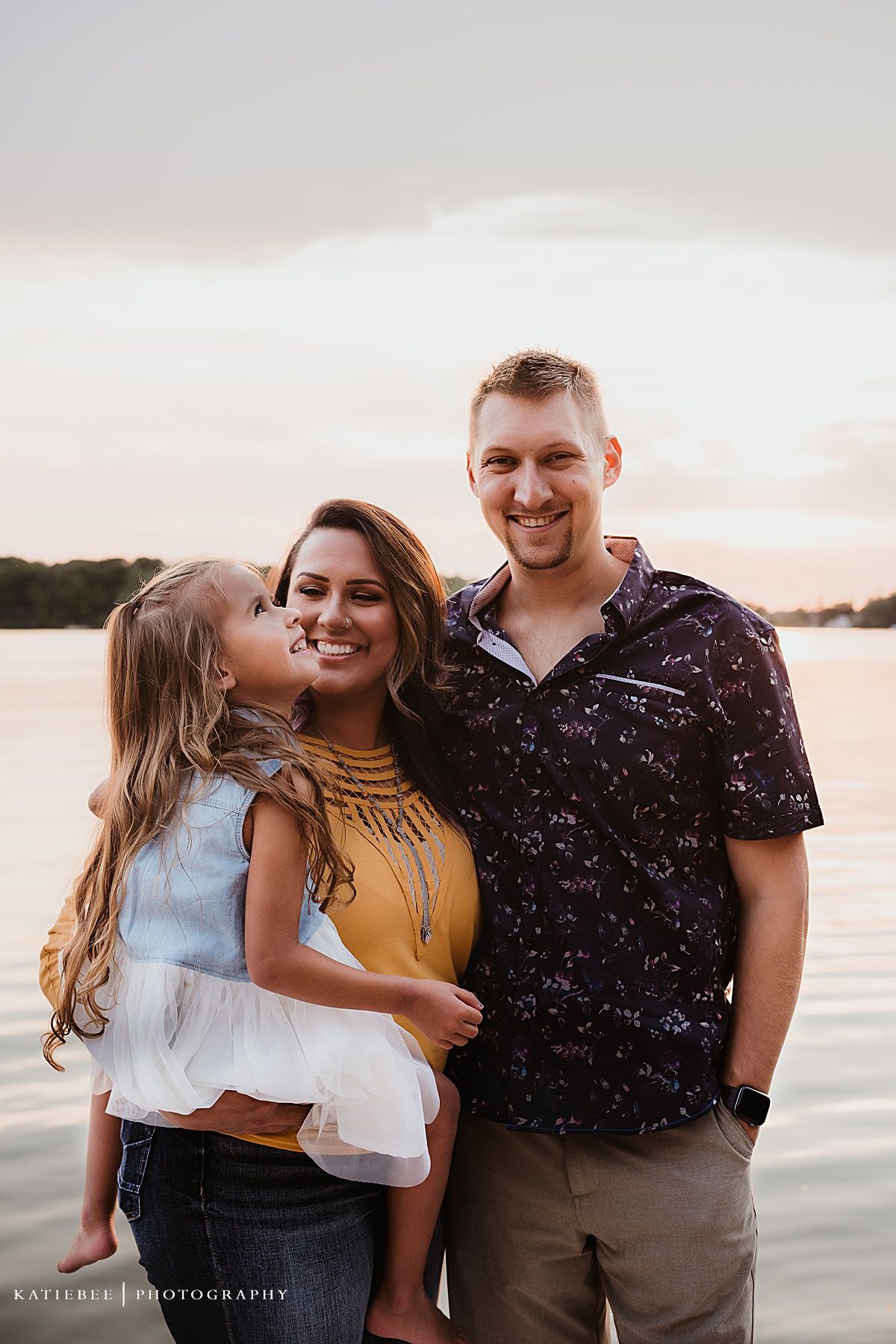 A happy family portrait captured during golden hour by the lake.