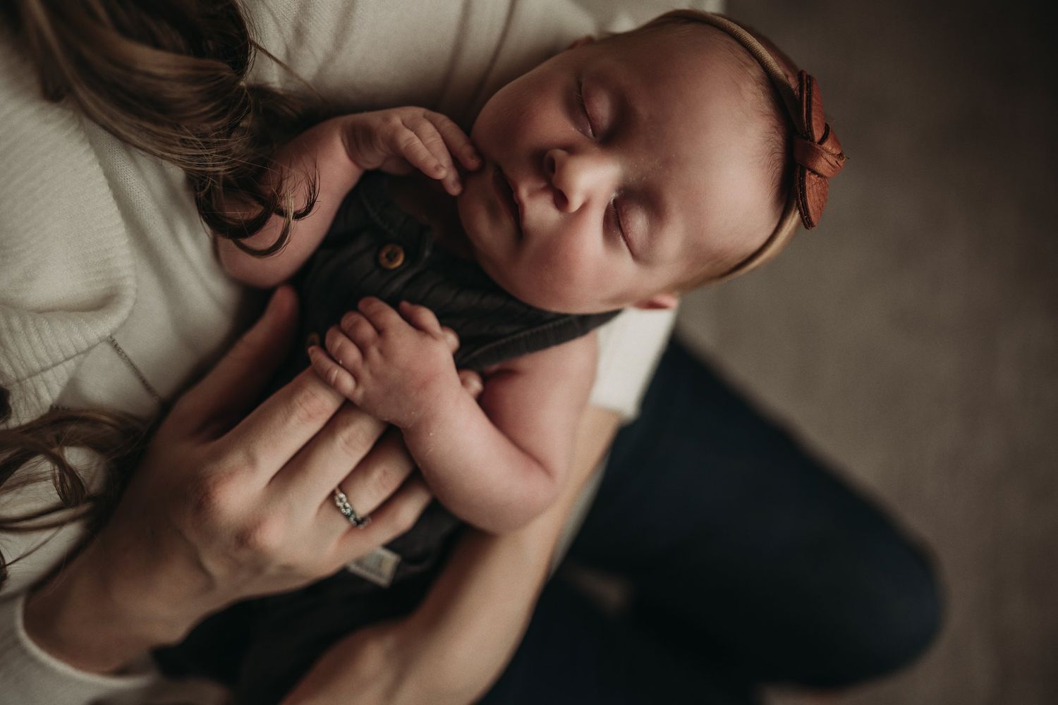 Sleeping infant in dark clothing nestled in parent's gentle embrace.
