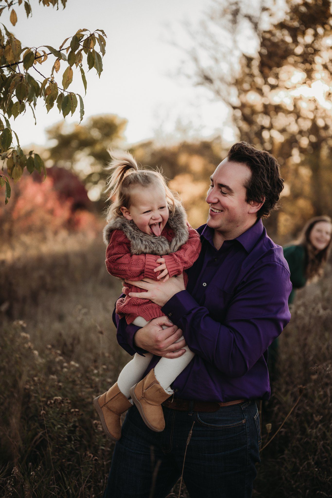 Candid laughter between parent and child during outdoor autumn photoshoot.
