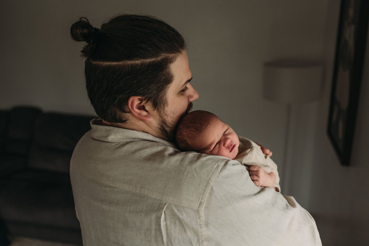 Peaceful moment of adult cradling sleeping newborn in soft lighting.