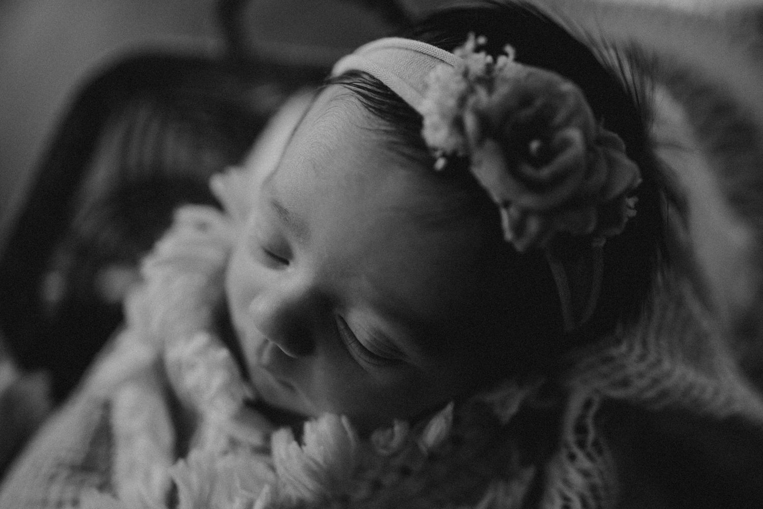 Peaceful black and white portrait of sleeping infant with floral headband.
