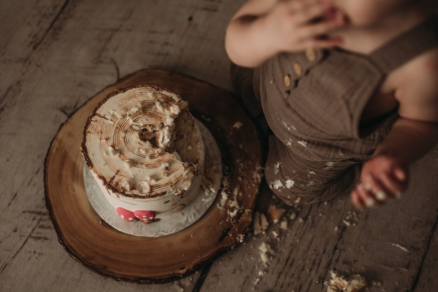 A demolished birthday cake with scattered crumbs on a rustic wooden surface.