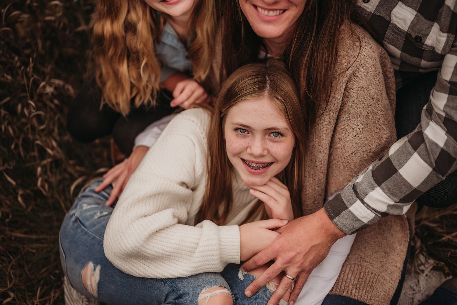 A cozy family cuddle captured in warm tones with rustic plaid and knit sweater details.