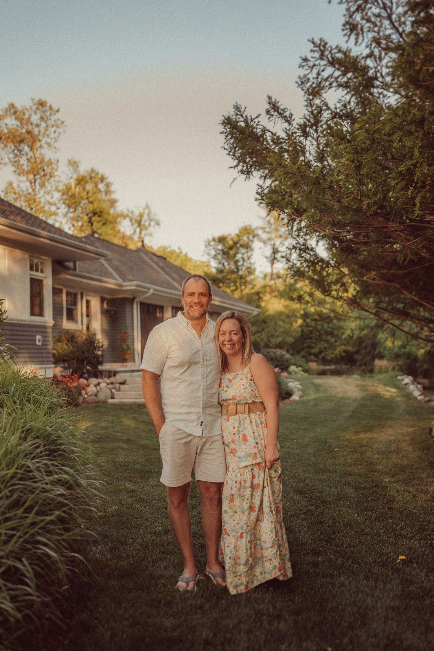 Couple standing in a landscaped backyard at sunset.