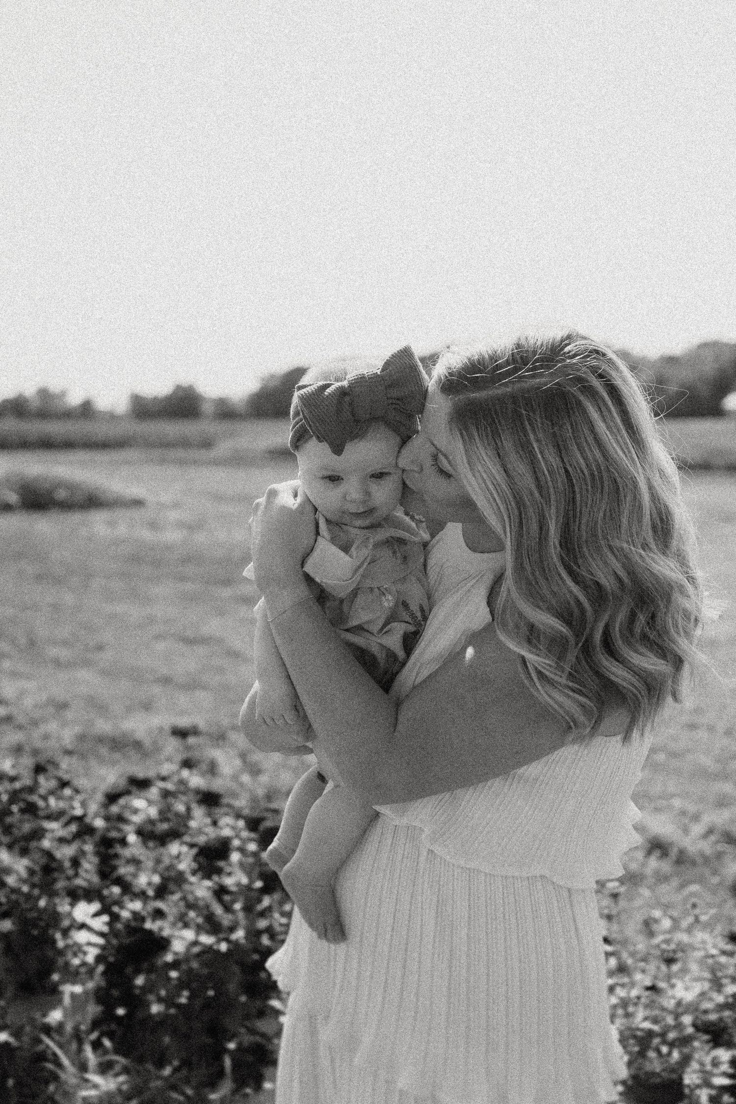 Black and white intimate portrait of mother and child in natural outdoor setting.