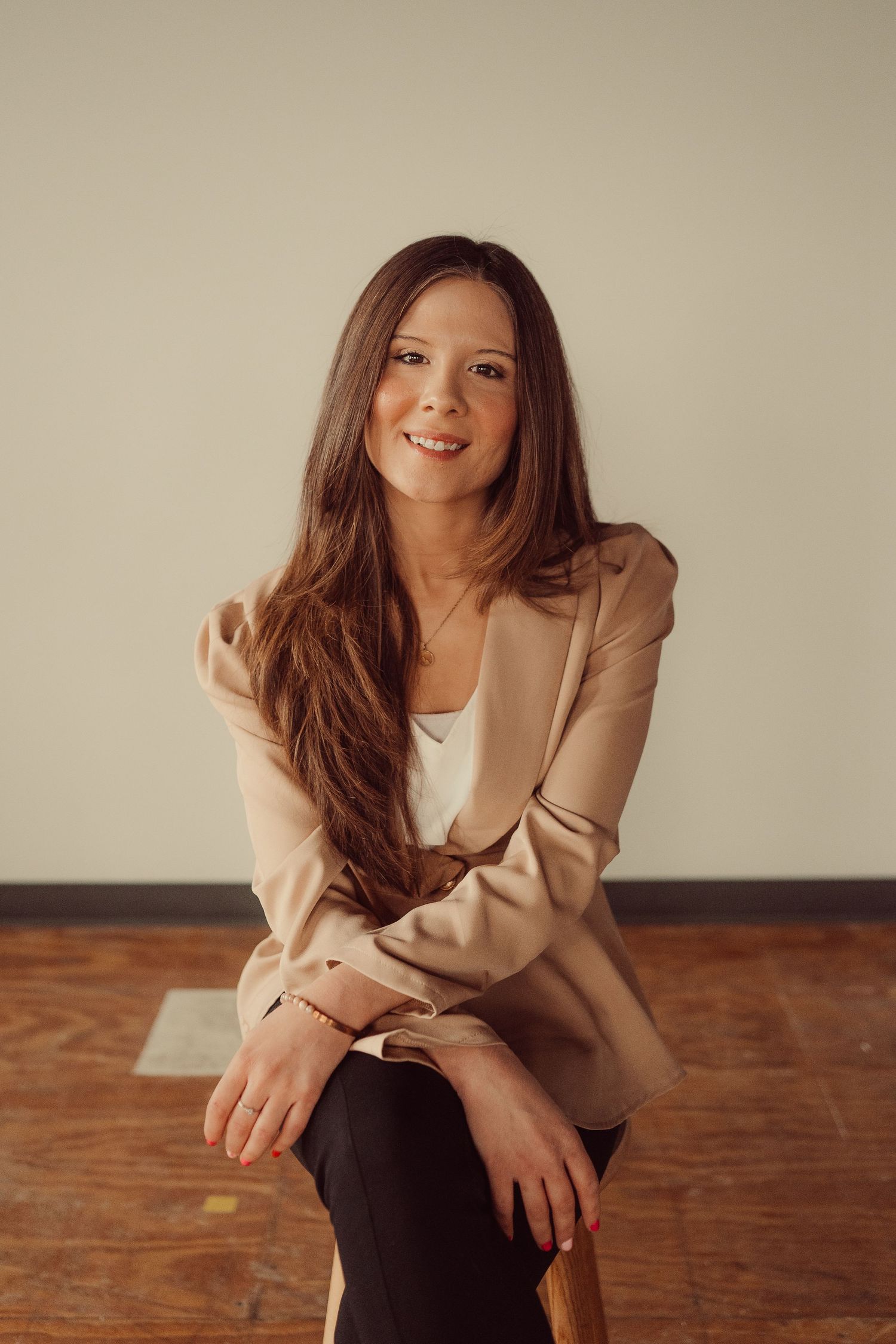 Warm toned professional portrait showing casual business style on wooden floor.