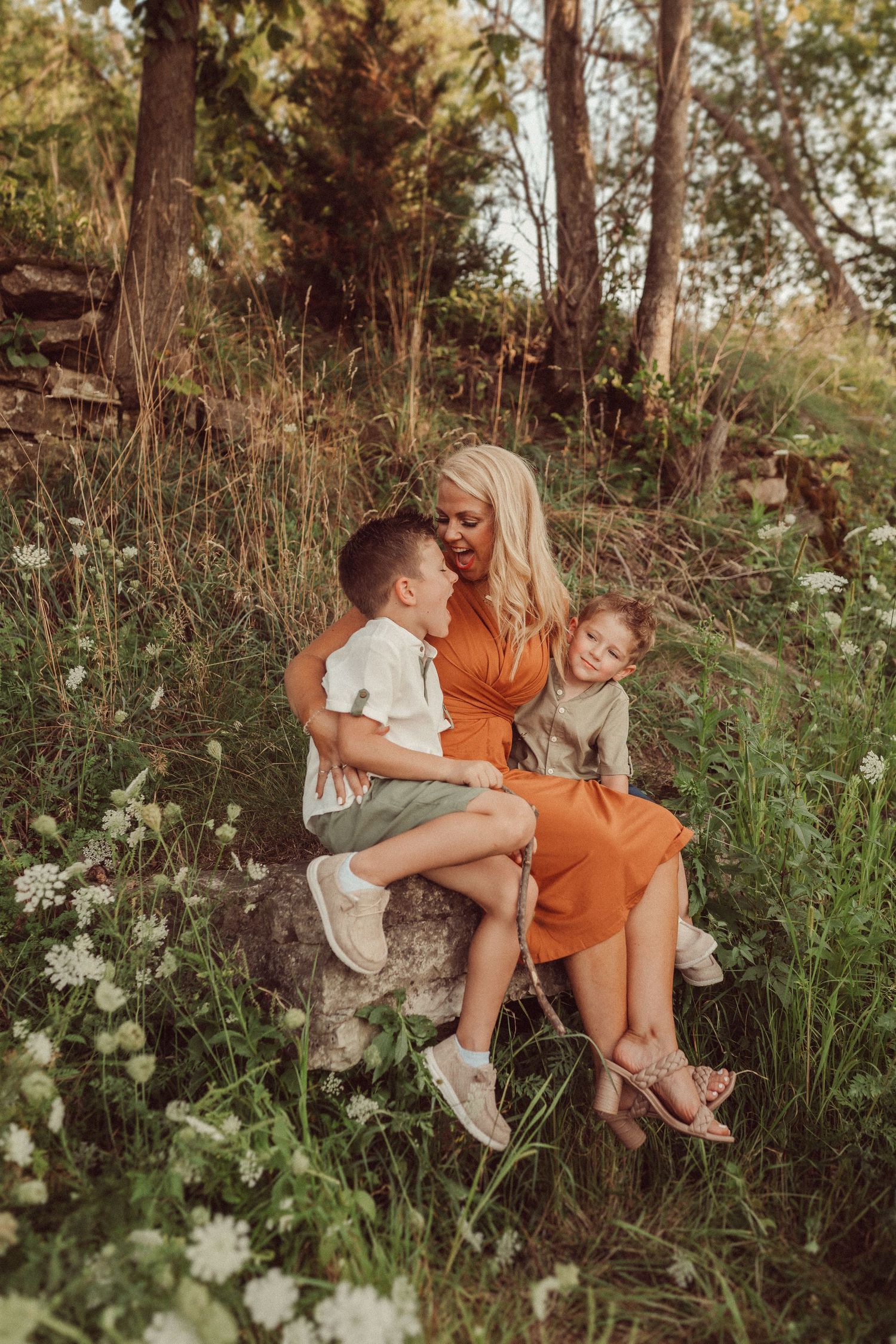 A tender family moment captured in warm tones among wildflowers and trees.