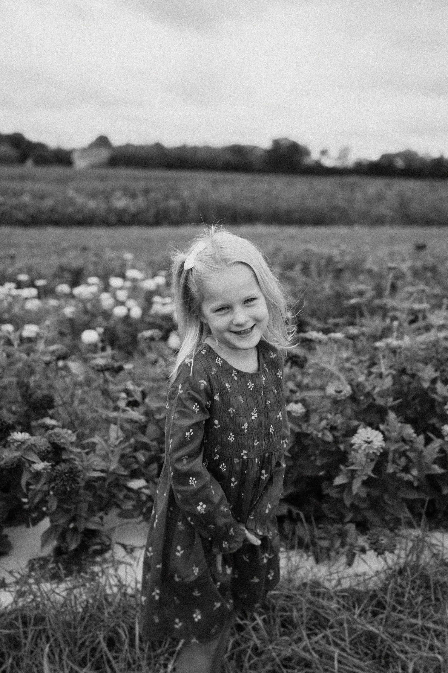 Black and white portrait showing pure joy among flowering plants in a field.