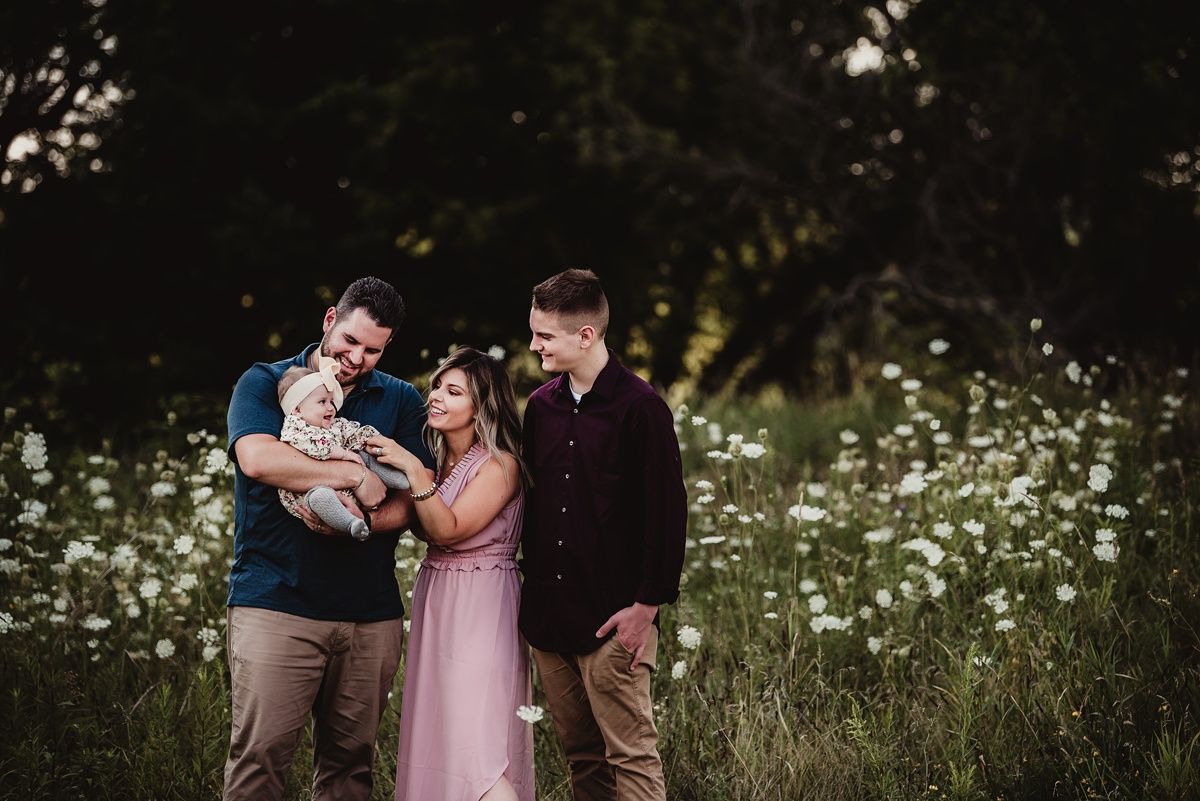 Family sharing joyful moment together in field of white wildflowers at dusk.