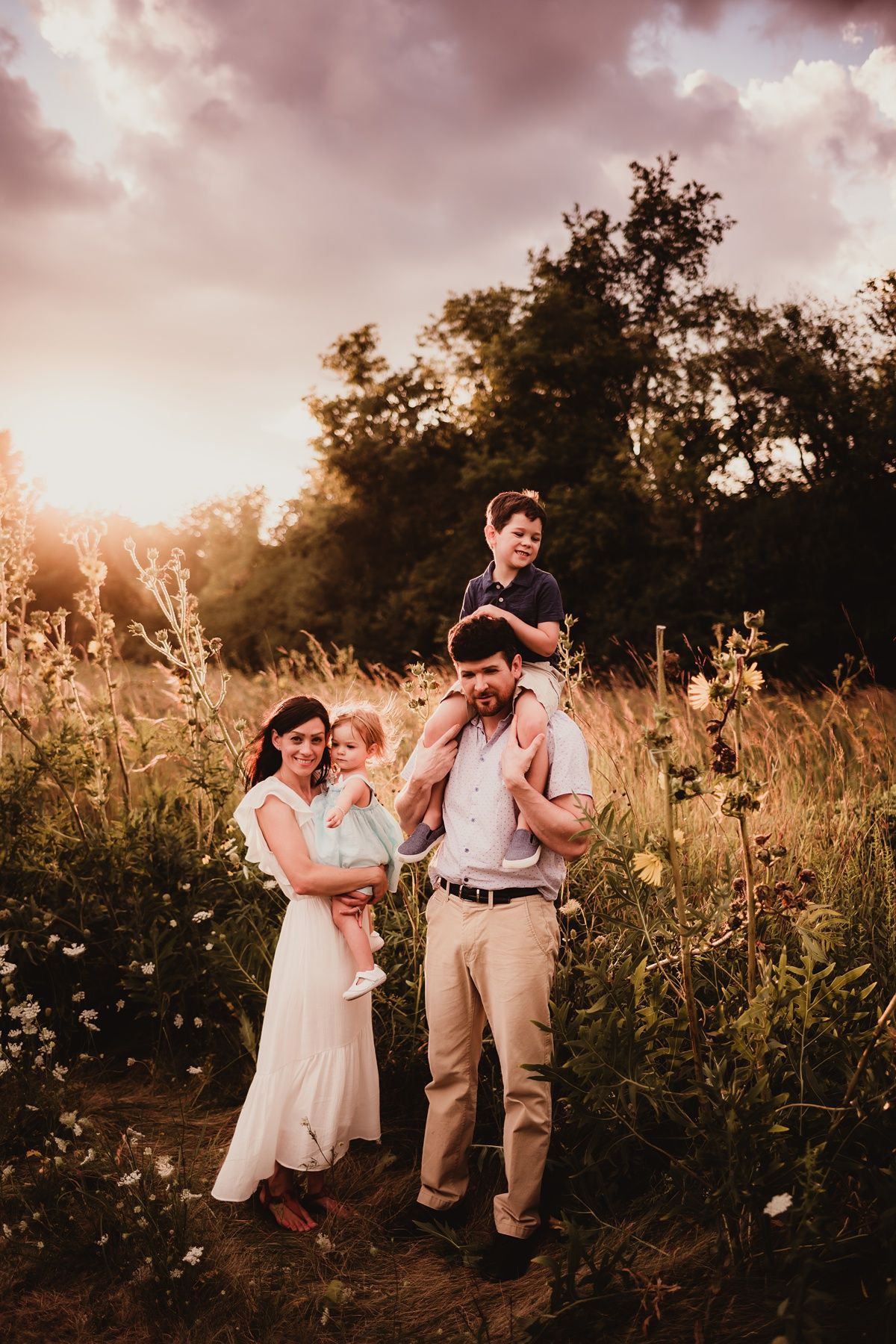 Family posing together in golden field during sunset photoshoot.