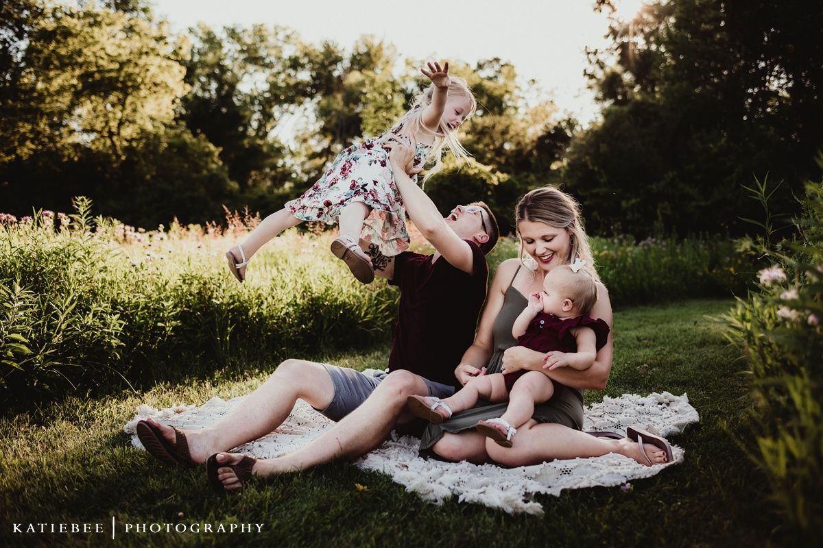 Black and white artistic photo of children playing on a blanket outdoors.