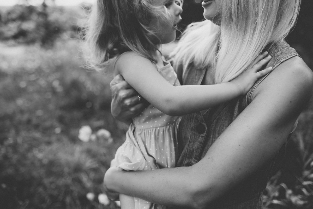 An intimate black and white moment of parent and child embracing in nature.
