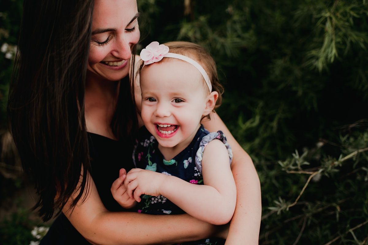 A candid moment of shared laughter and joy captured outdoors against green foliage.
